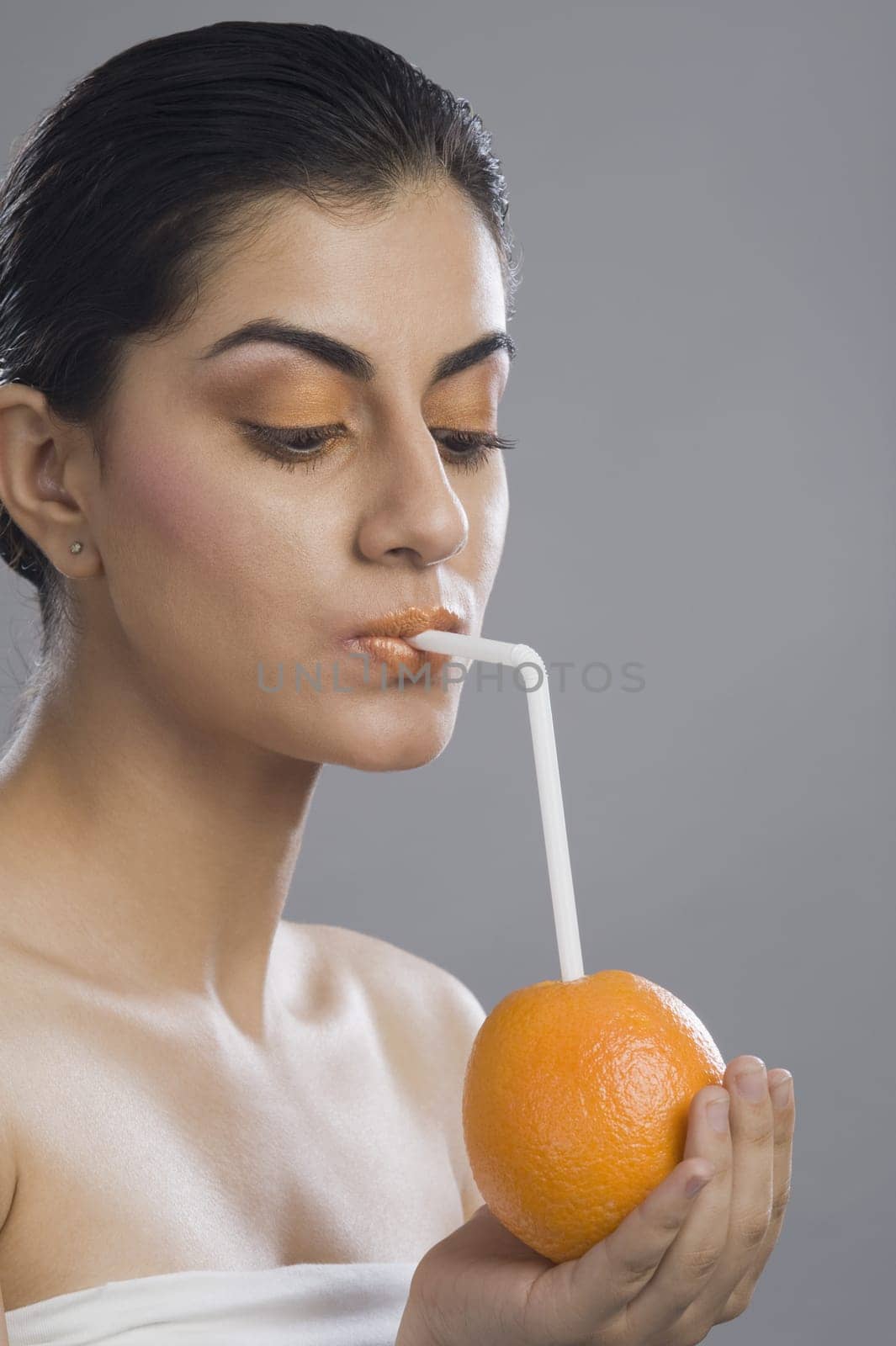 Close_up of a woman drinking from a straw in an orange