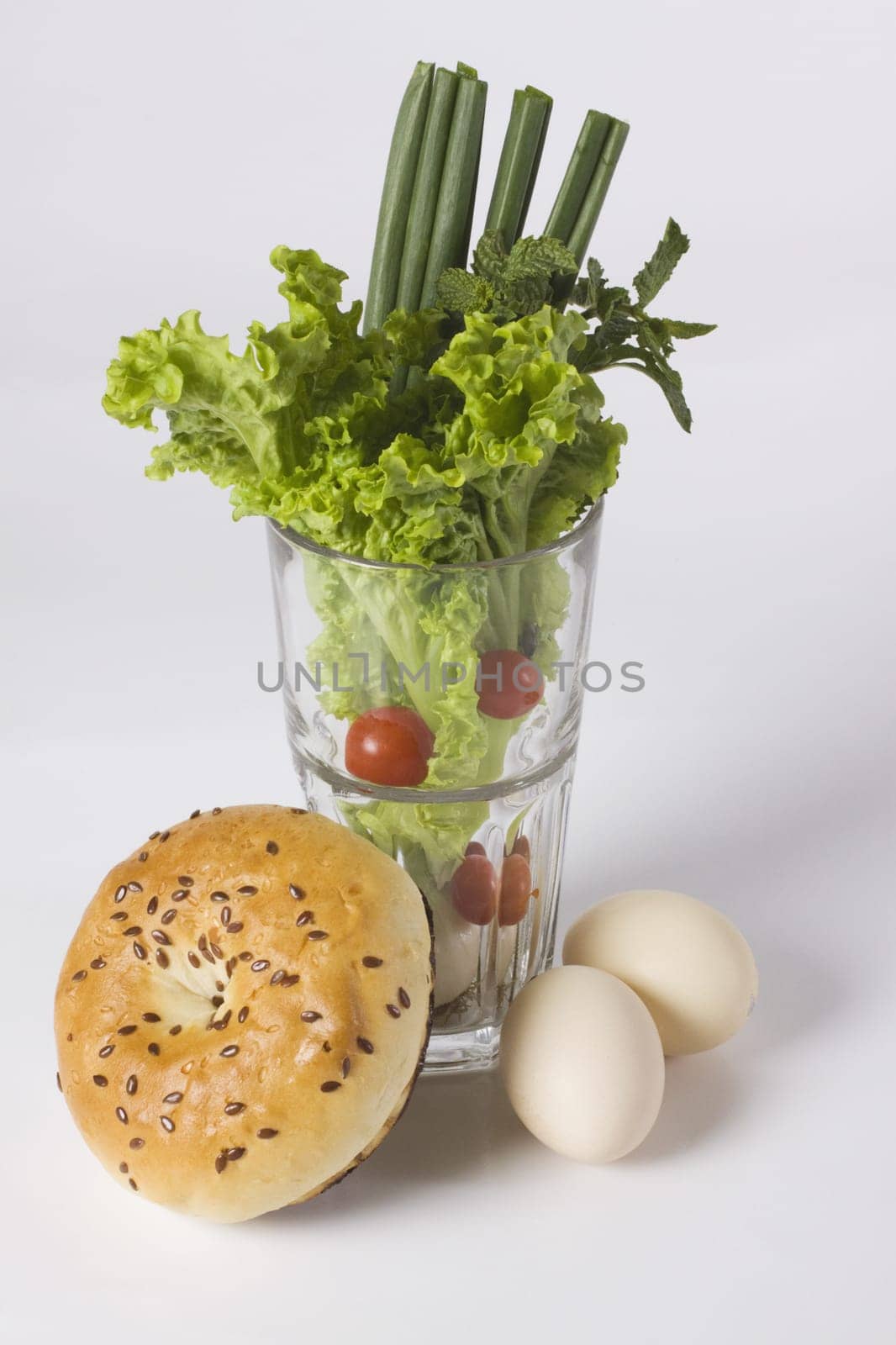 Glass full of vegetables with a bagel and brown eggs