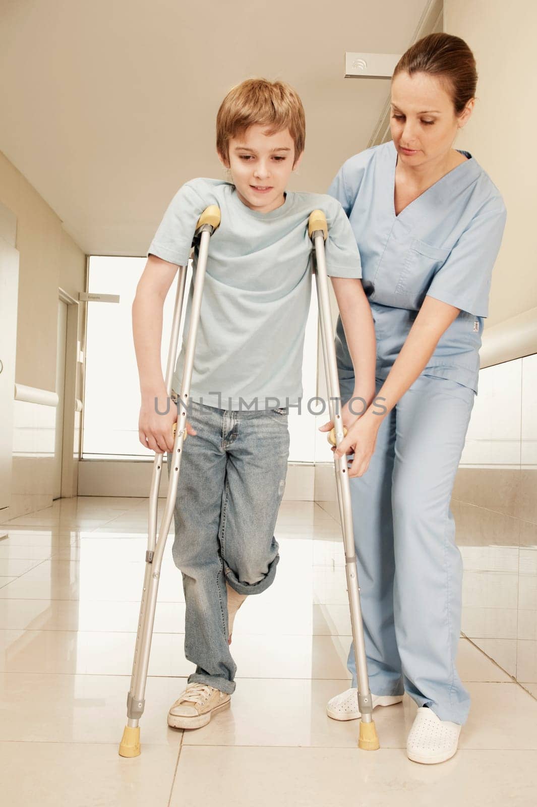 Female nurse assisting a boy on crutches