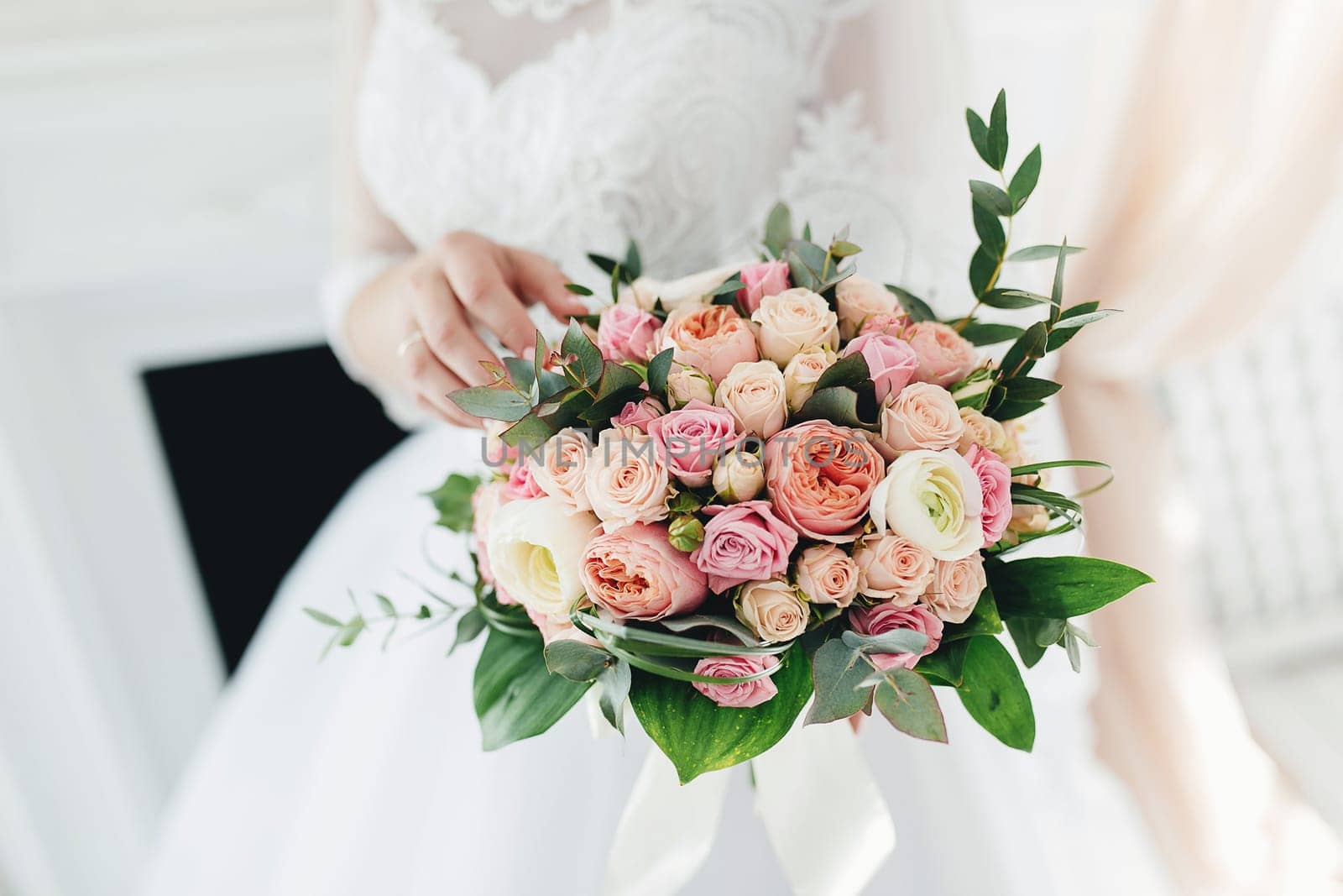 Bride in white dress is holding wedding bouquet. High quality photo