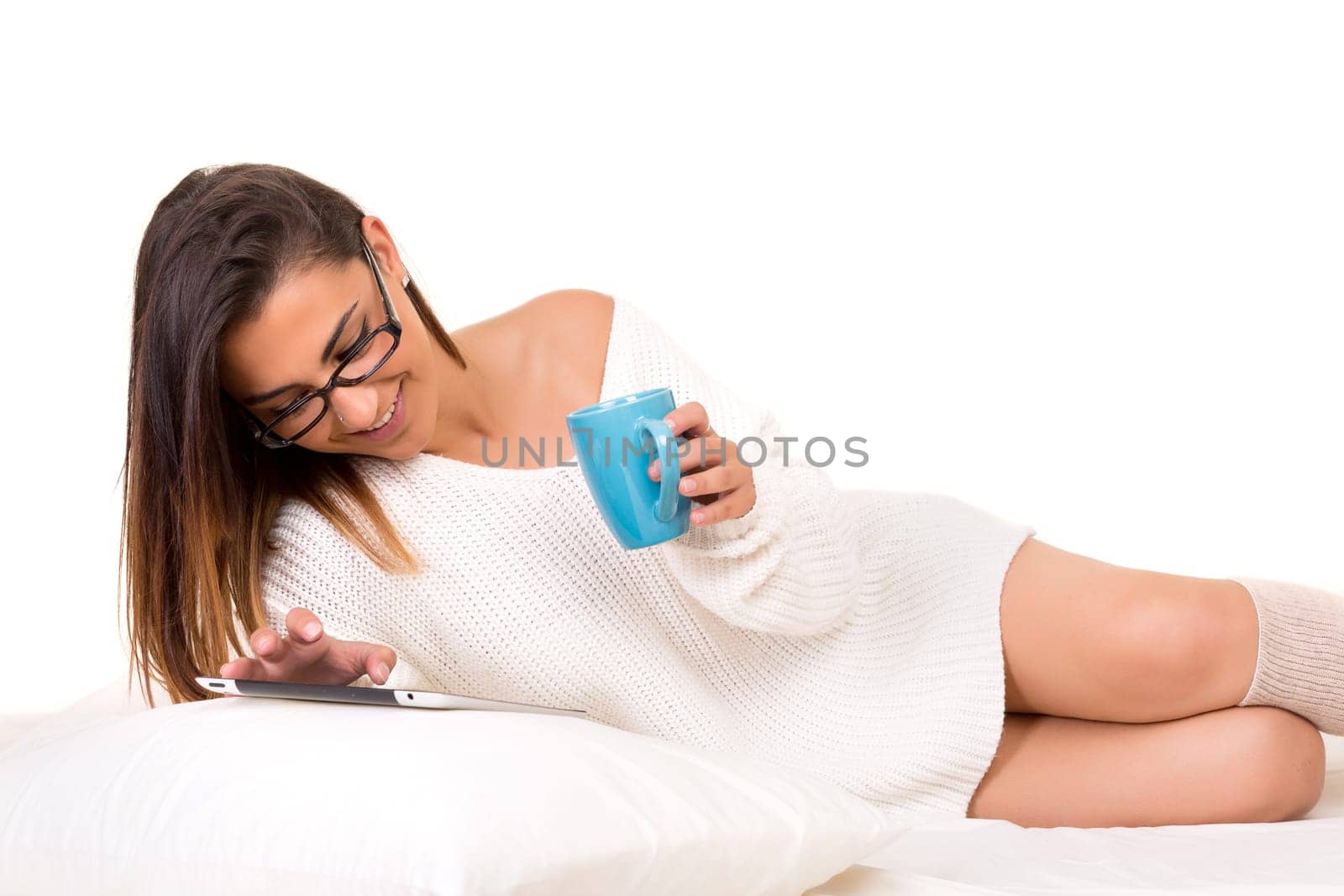 Young beautiful woman in bed, working or relaxing with her computer