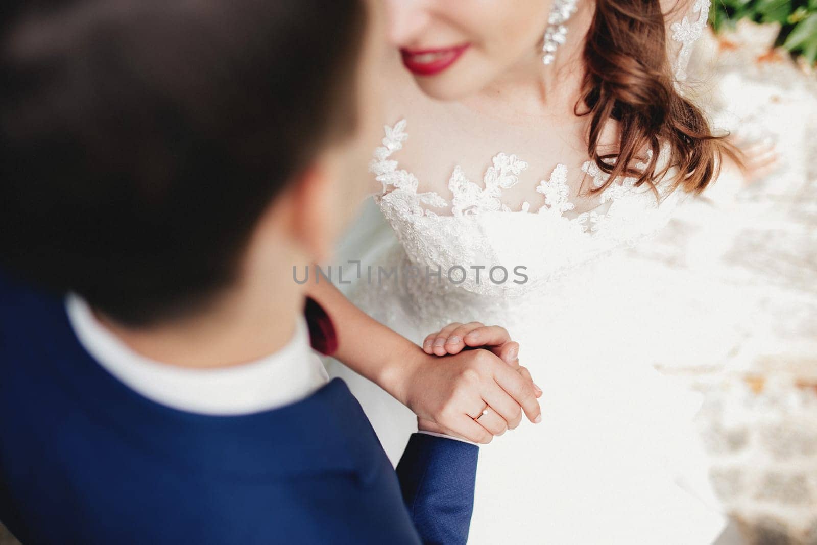 Groom holds bride hand in white dress. Bride is smiling. High quality photo