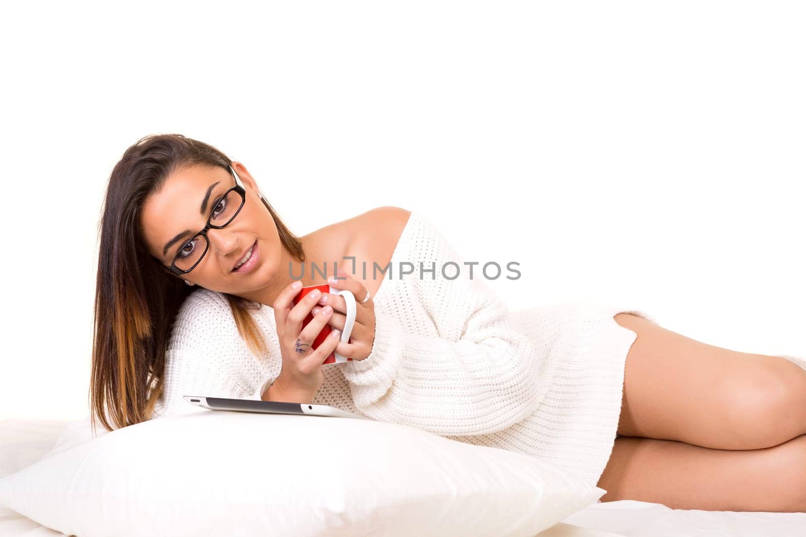 Young beautiful woman in bed, working or relaxing with her computer
