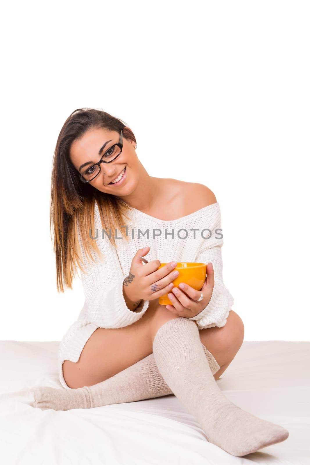 Young beautiful woman having breakfast in bed while working or relaxing with her computer