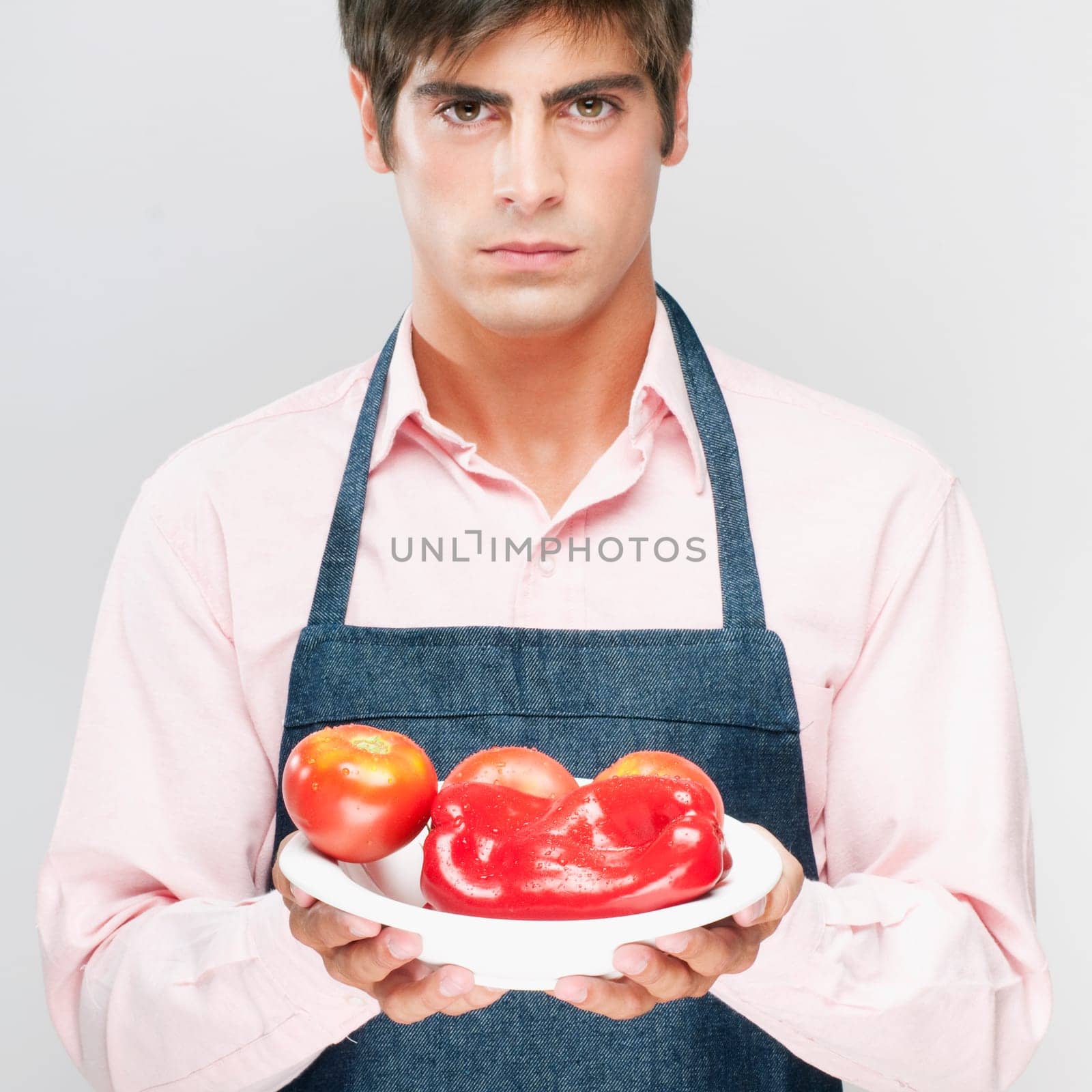 Man holding a plate of red bell peppers and tomatoes