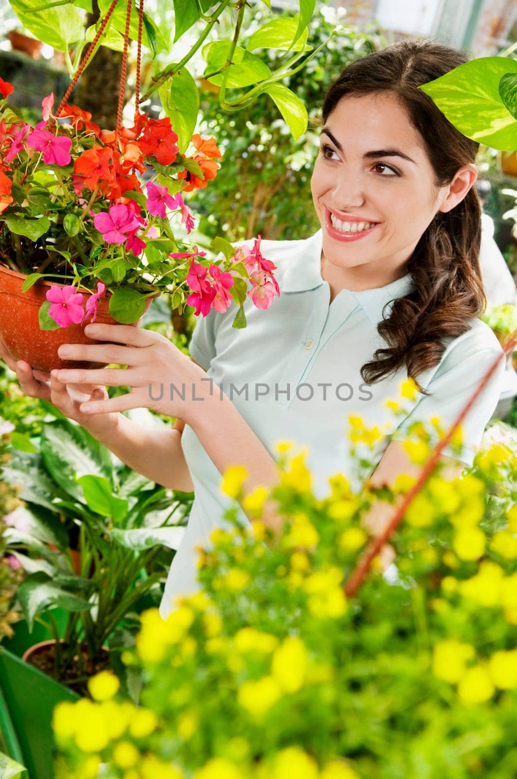 Woman holding a hanging basket in a greenhouse