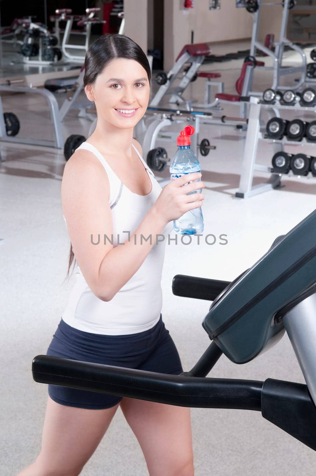 Portrait of a woman holding a water bottle on a treadmill