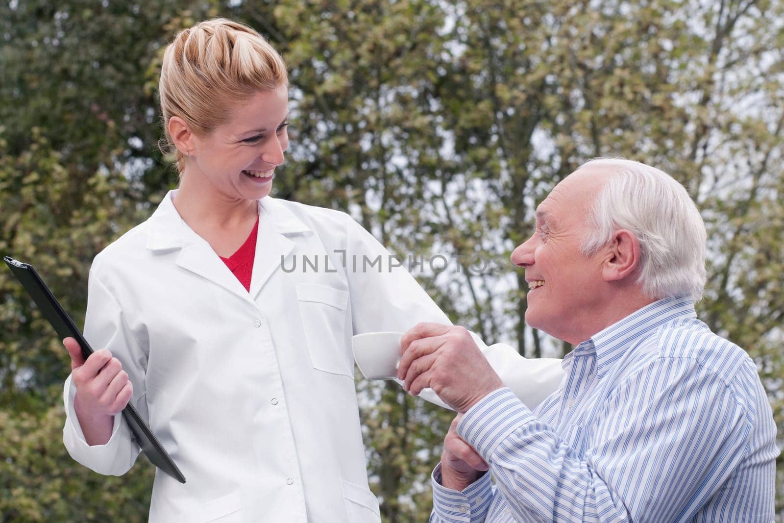 Man drinking tea with a doctor standing beside him