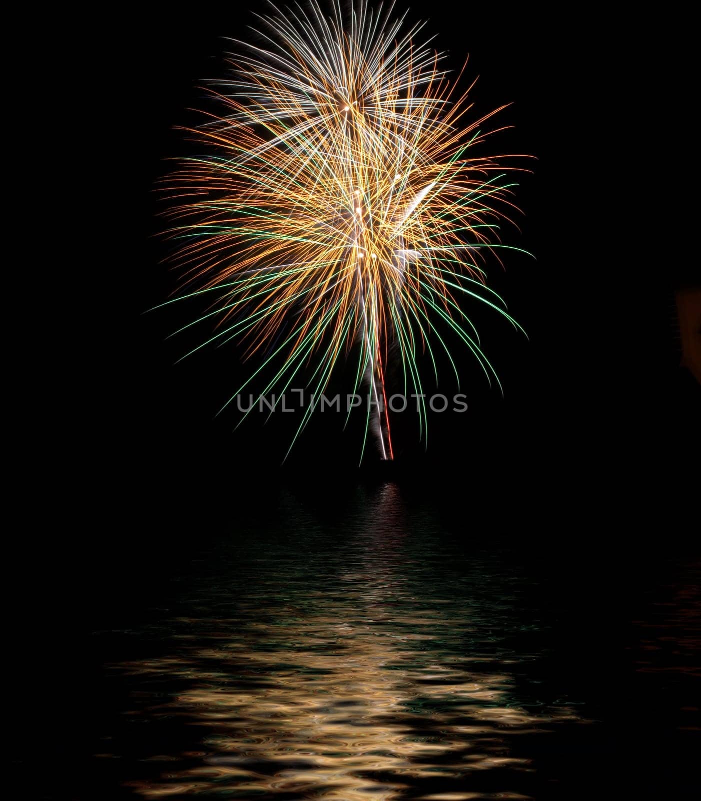 Exploding fireworks with reflexes on water at night