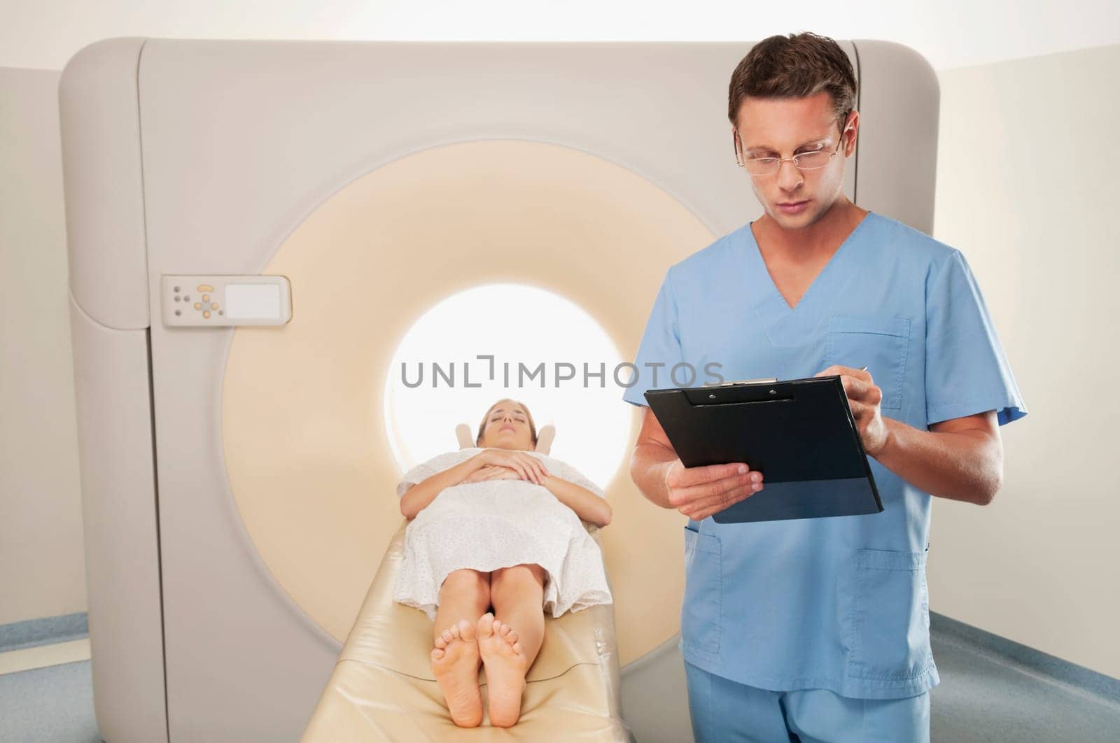 Surgeon checking medical report with a patient undergoing an MRI scan