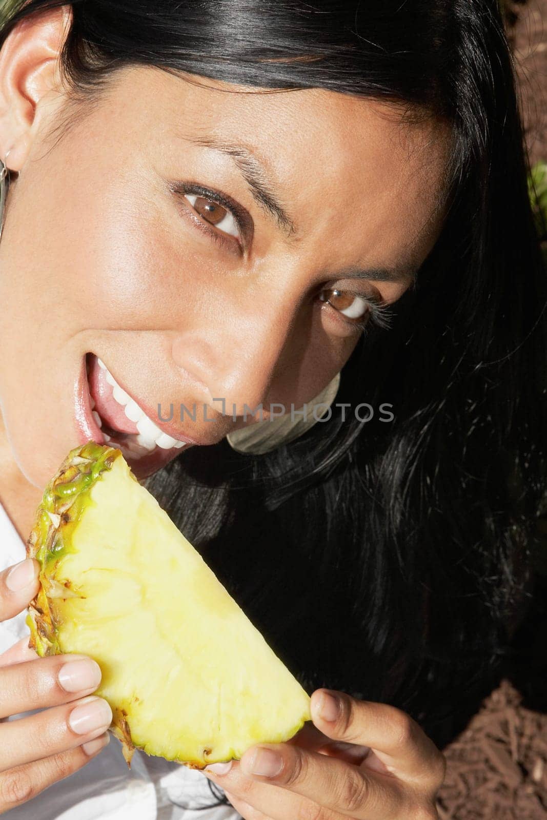 Portrait of a woman eating a slice of a pineapple