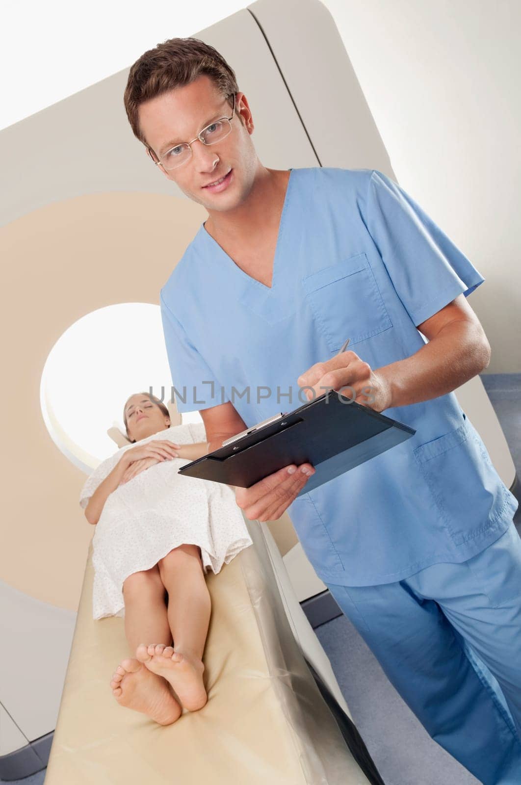 Surgeon checking medical report with a patient undergoing an MRI scan in background
