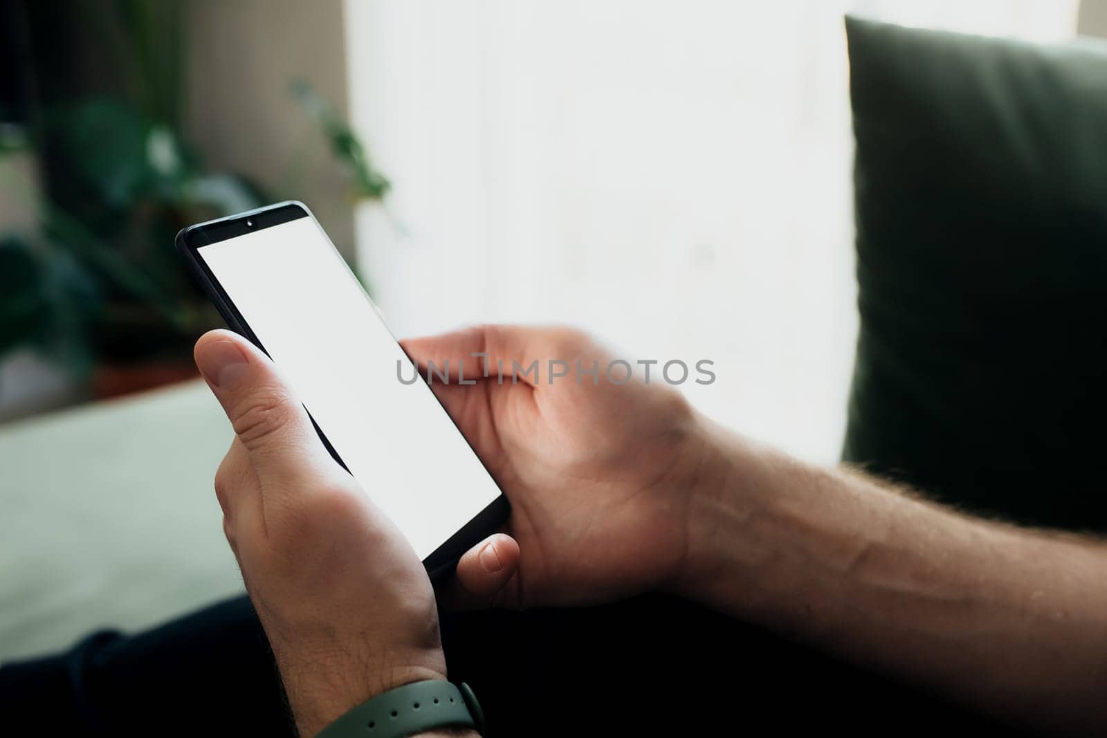 Man is holding smartphone with white screen. Blurred background. High quality photo