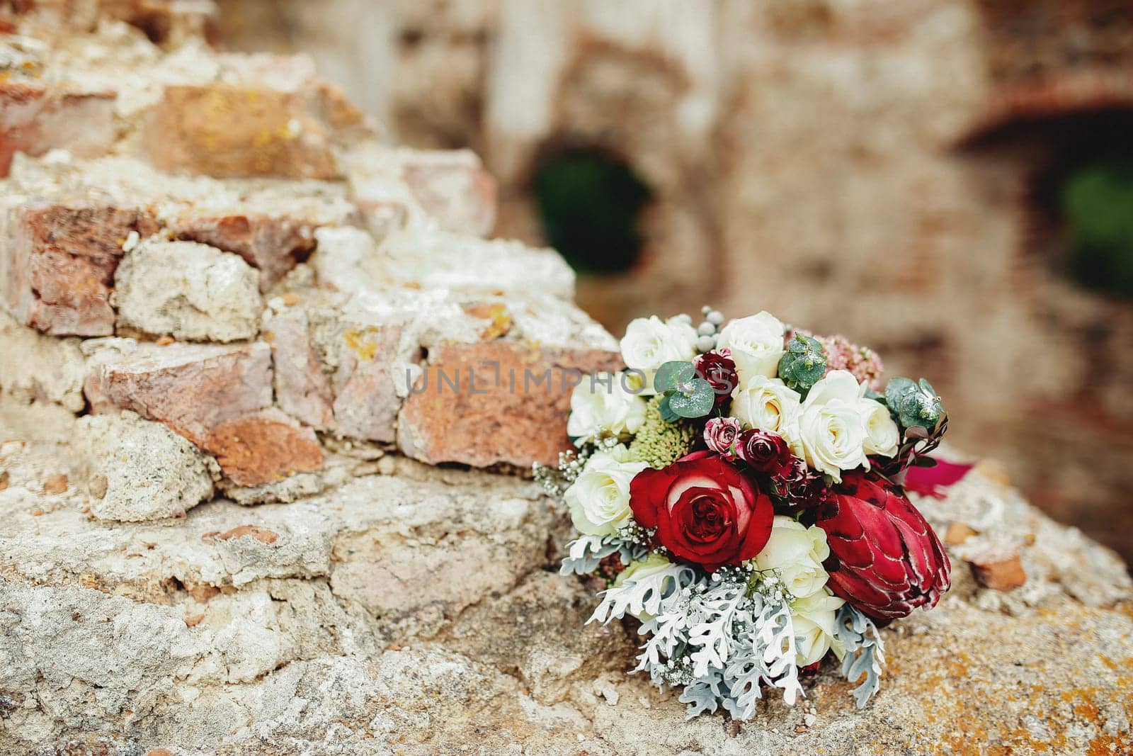 Wedding bouquet on the broken brick fence. Blurred background. High quality photo