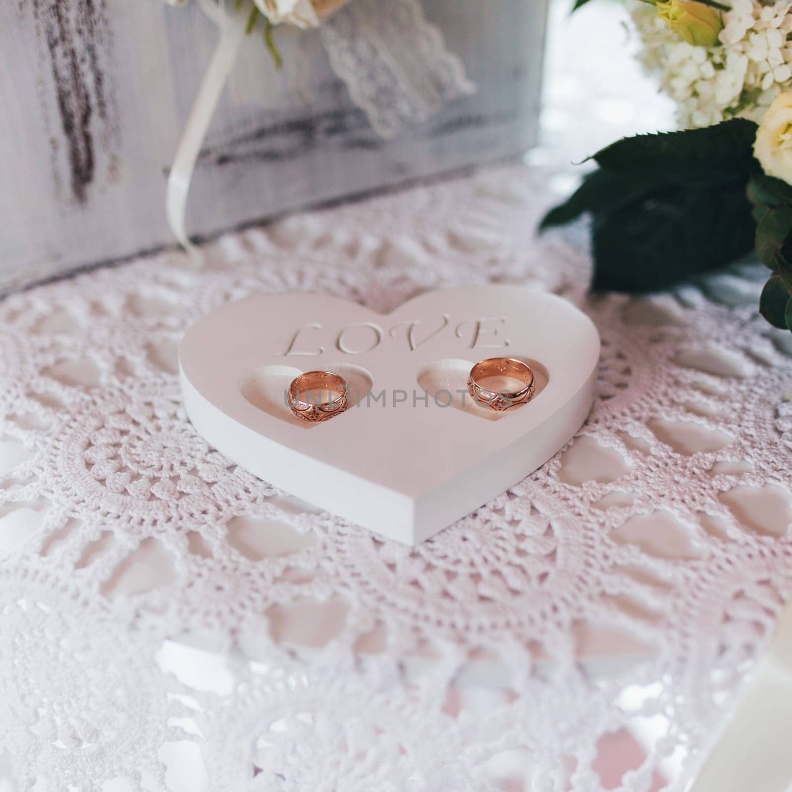 Heart shape object with love word and wedding rings on rustic stitched napkin. Blurred background. High quality photo