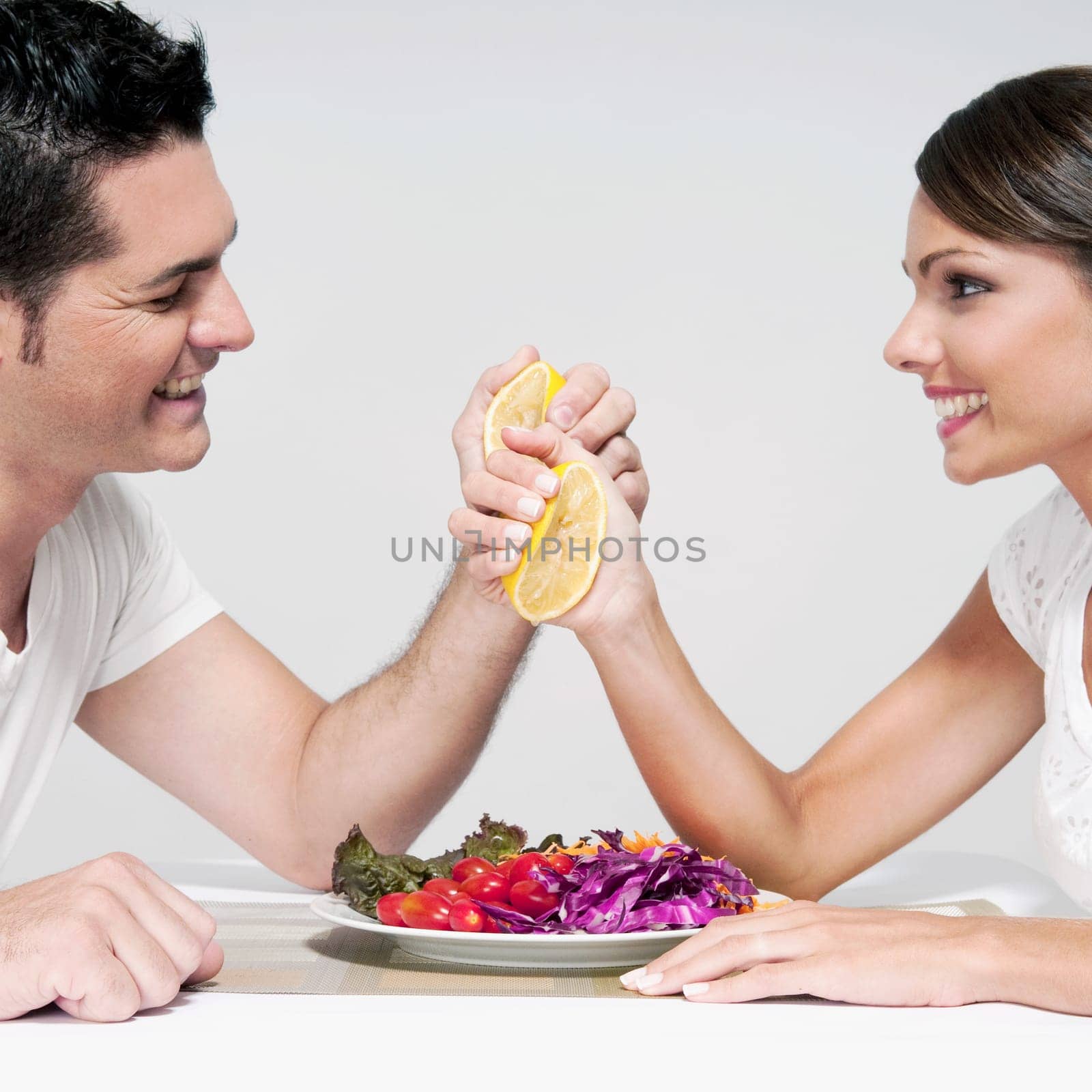 Couple squeezing orange halves over a salad