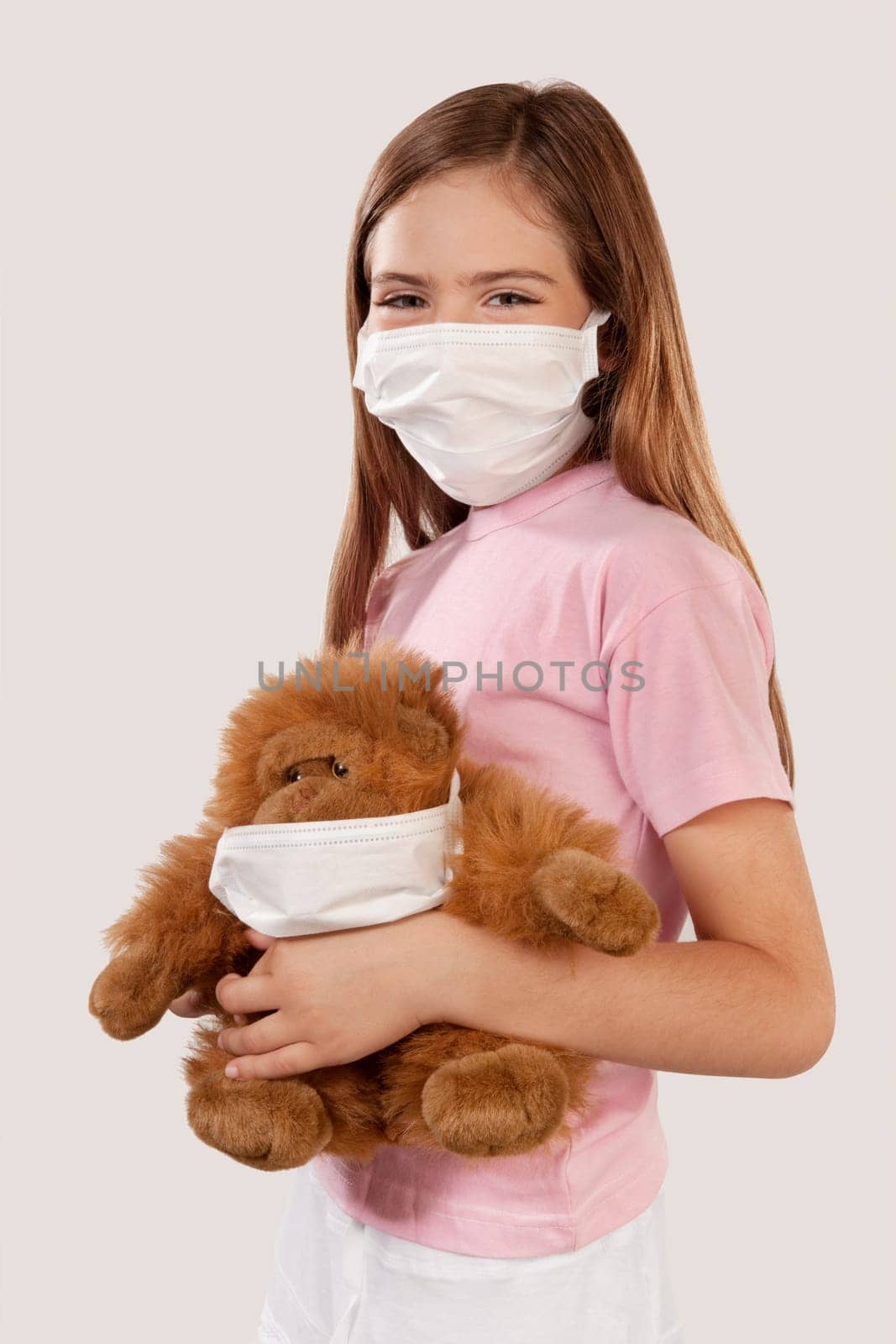 Girl wearing flu mask and holding a teddy bear