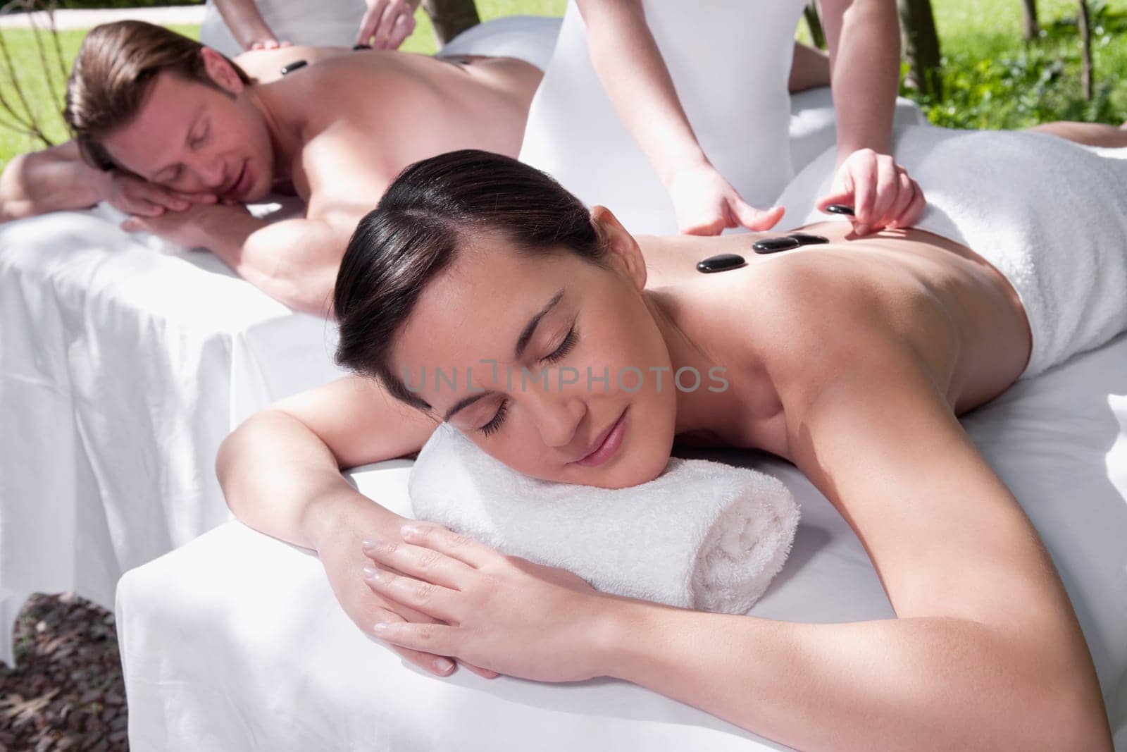 Couple receiving hot stone therapy from massage therapists