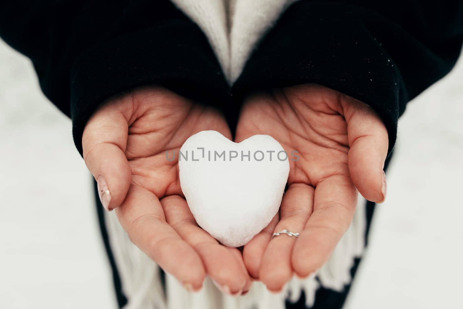 Snow heart snowball in girl gloved hands. Blurred background. High quality photo