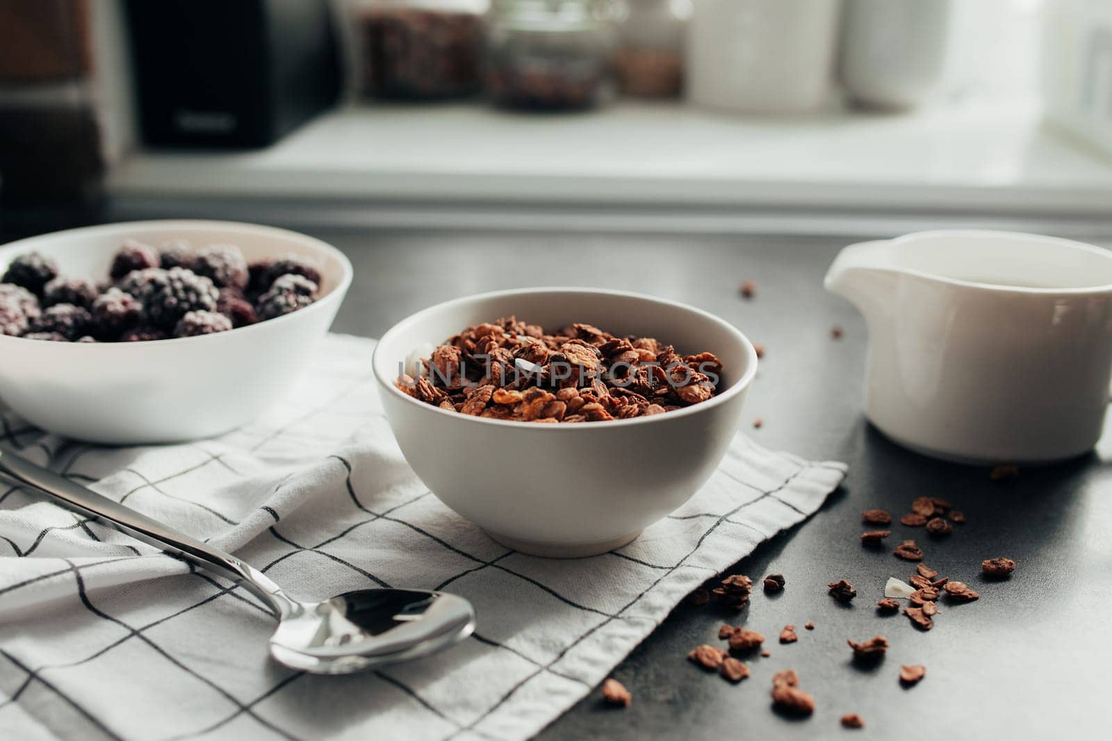 Frozen blackberries, granola, cream, towel on table. Blurred background. High quality photo