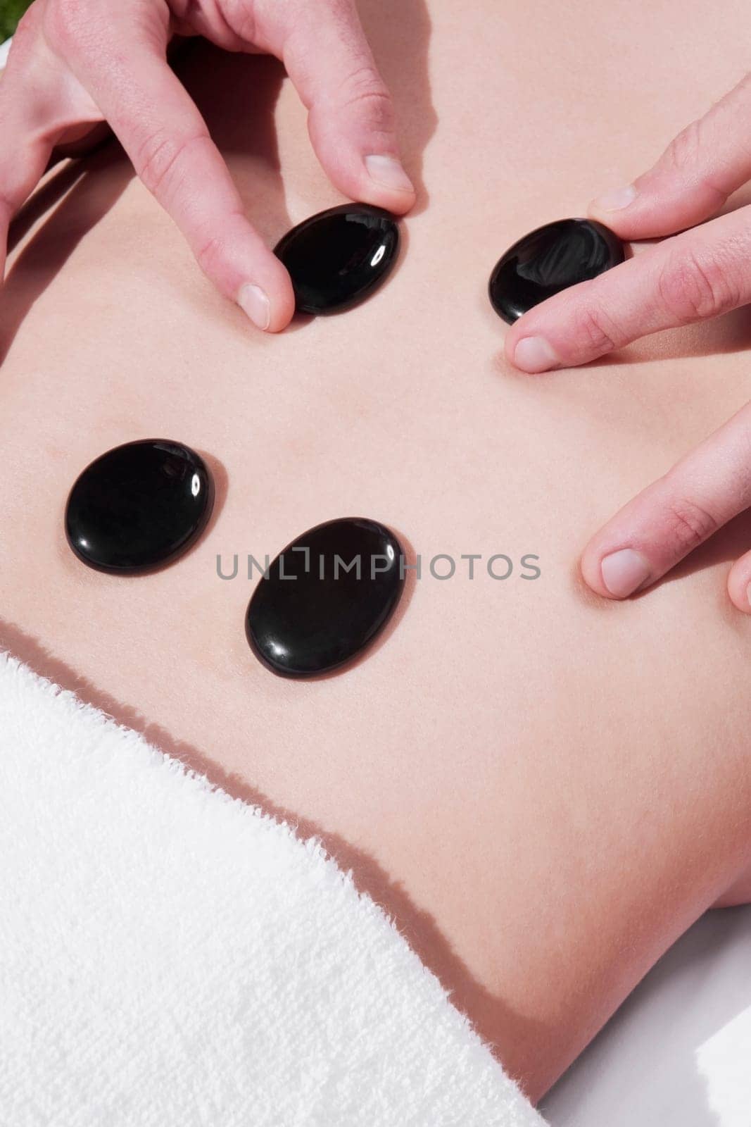 Woman receiving hot stone therapy from a massage therapist