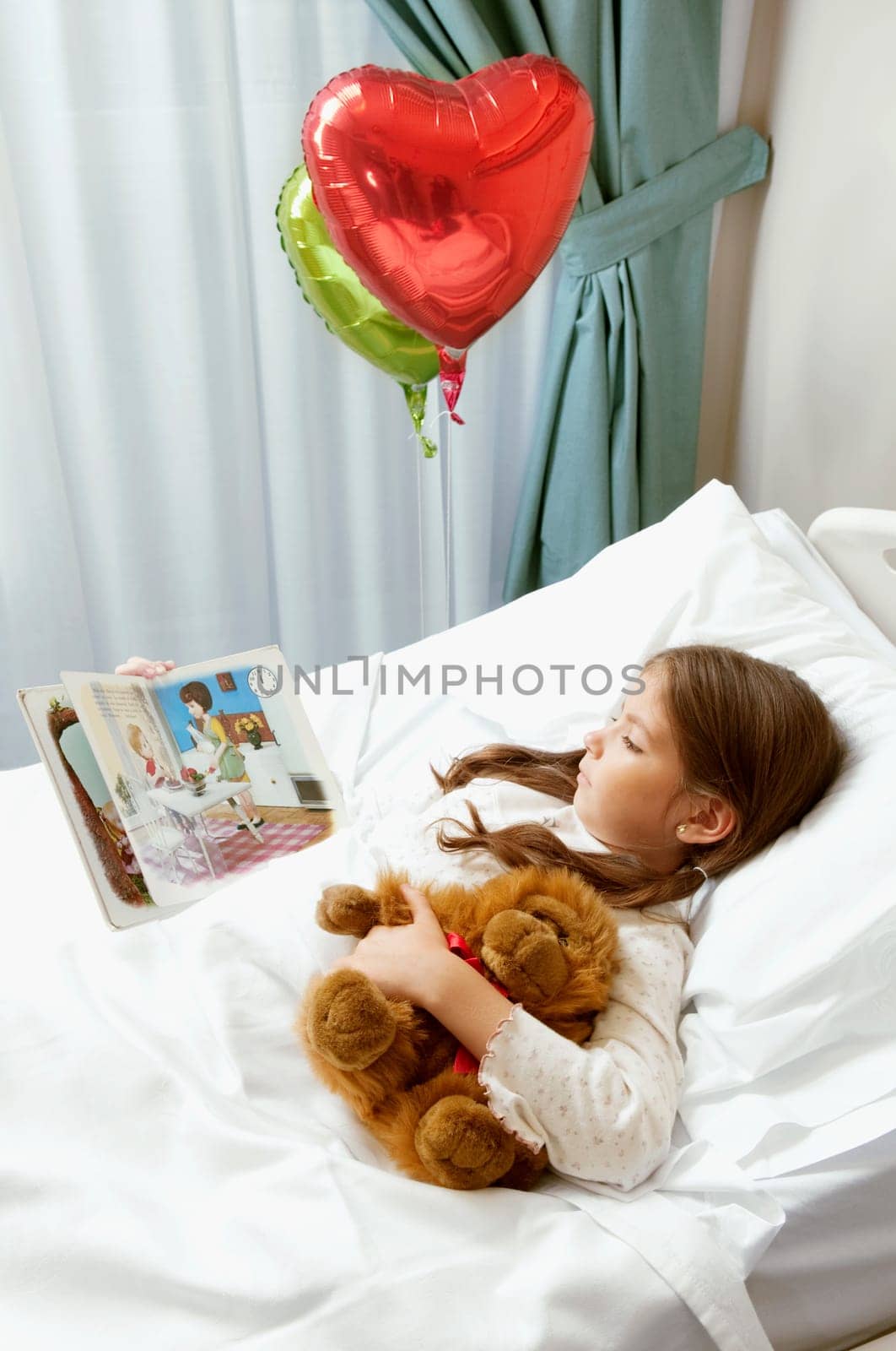 Girl reading a comic book on a hospital bed