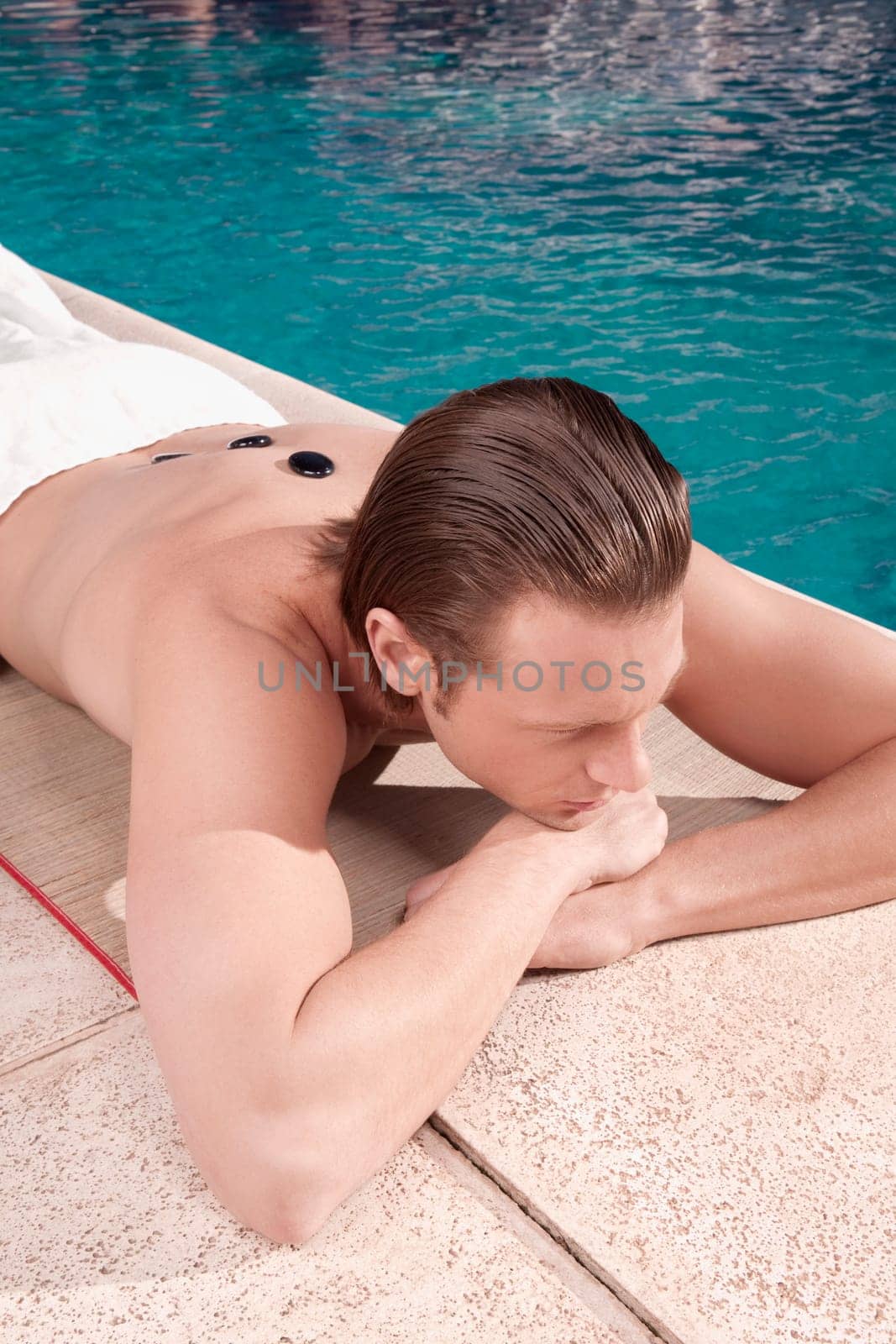 Man receiving hot stone therapy at the poolside