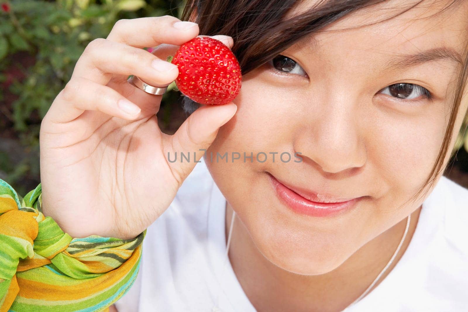 Woman holding a strawberry and smirking