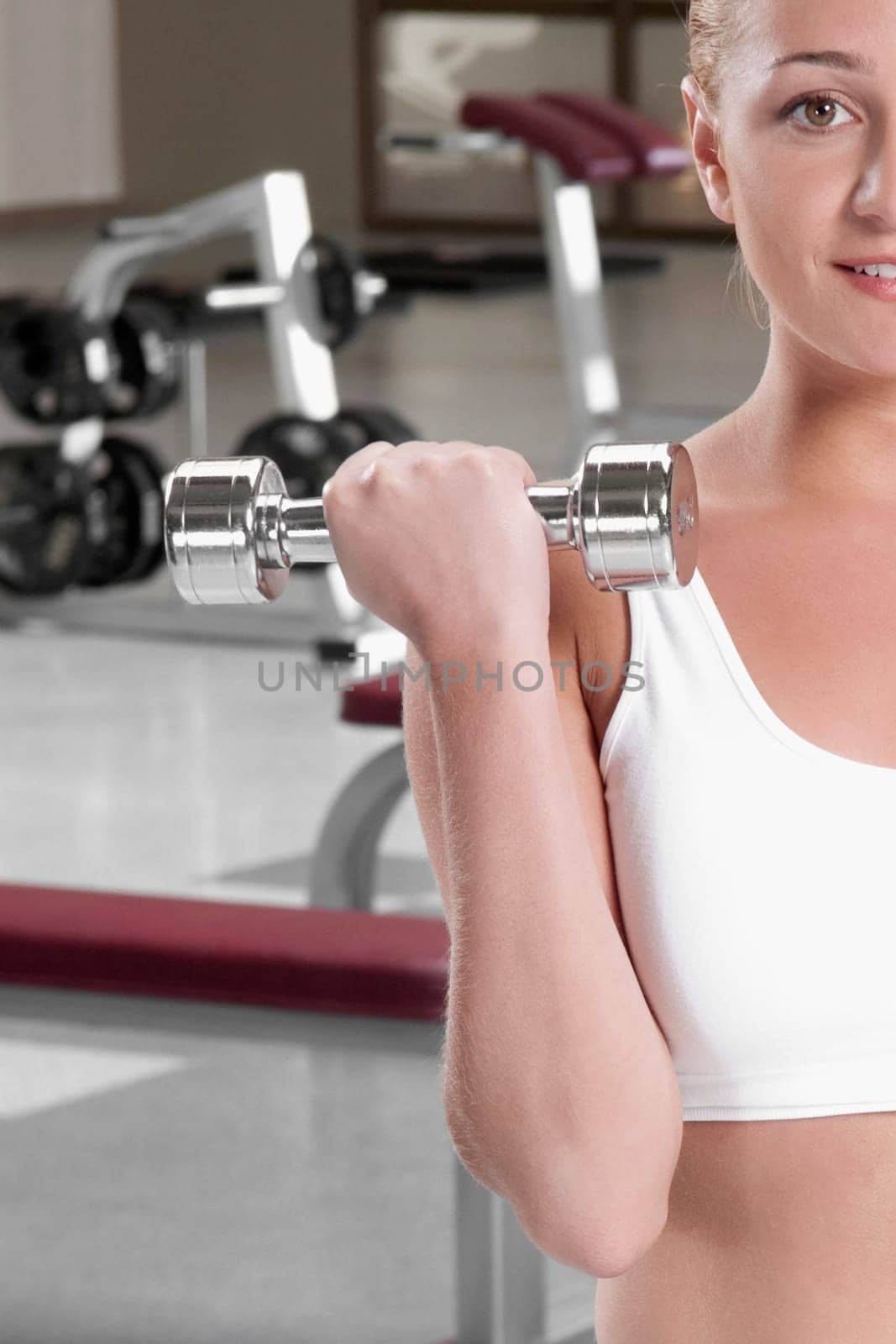 Close_up of a woman exercising with dumbbells at gym