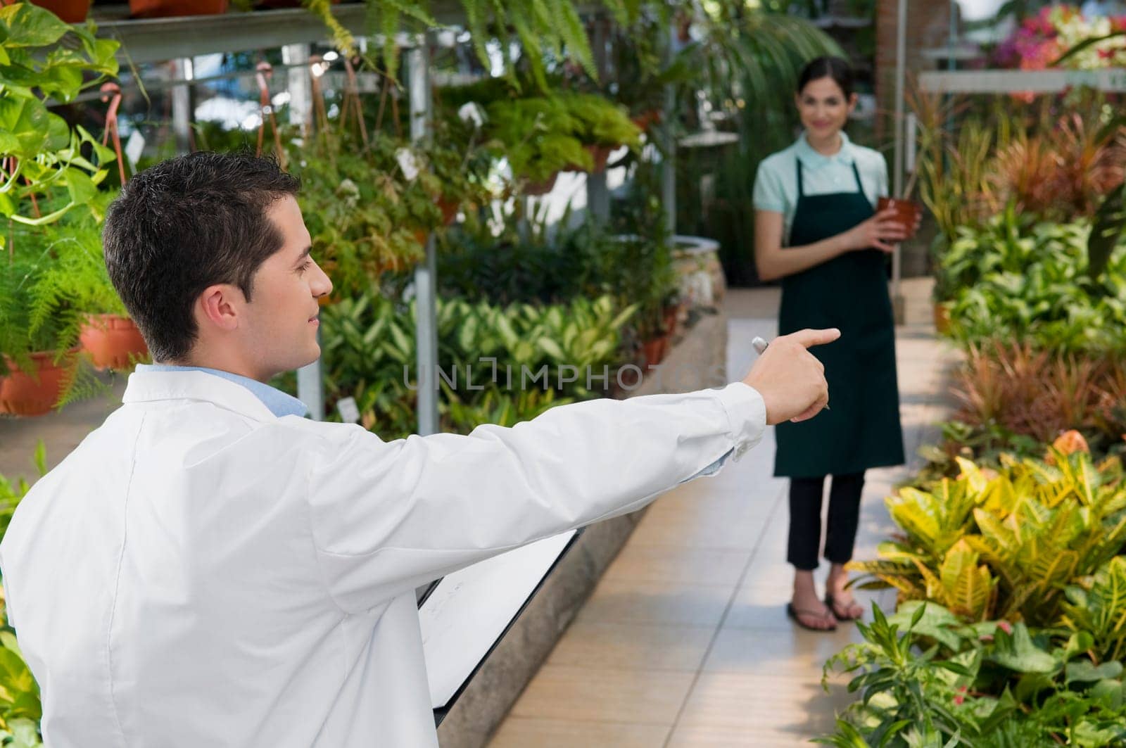 Scientist giving instructions to a woman in a greenhouse
