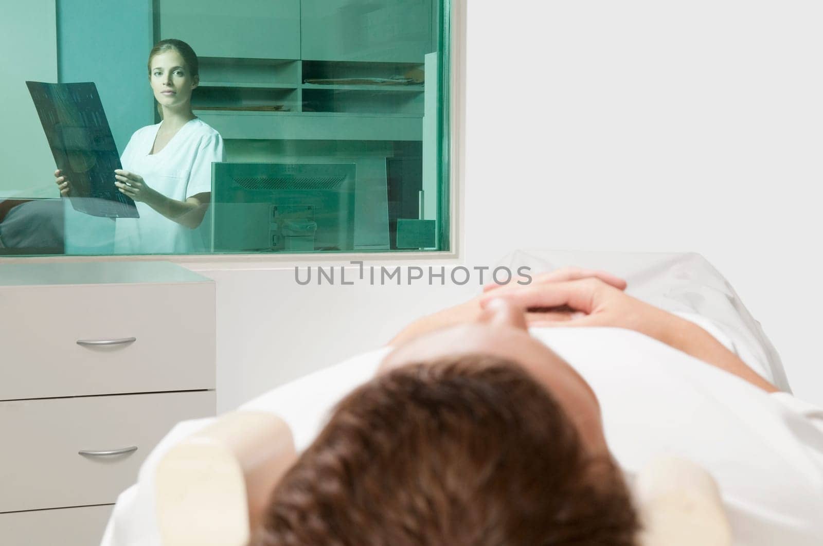 Patient going through an MRI scan with a doctor analyzing an X_Ray report in background