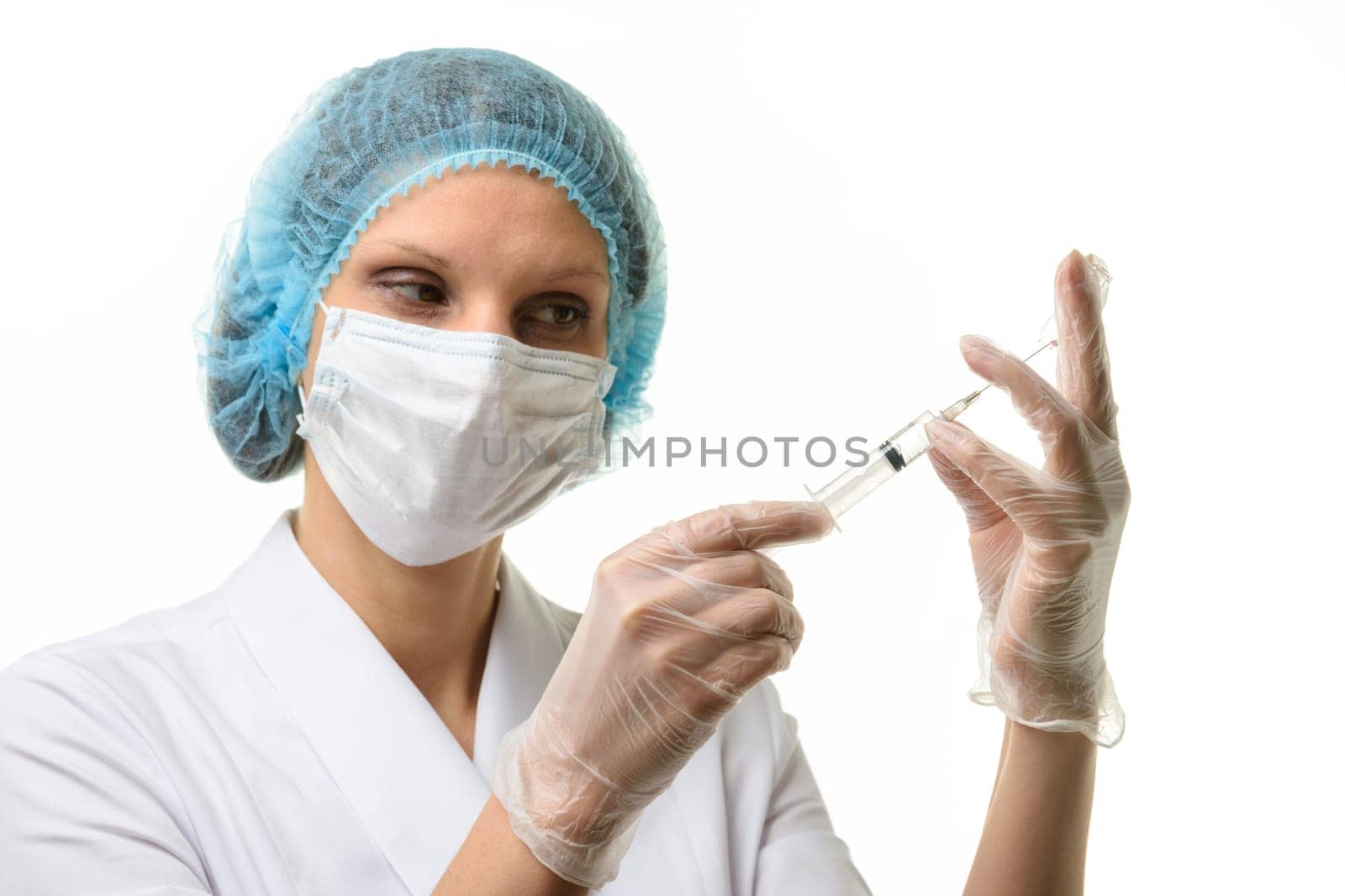 Nurse in mask and gloves draws medicine with a syringe from an ampoule