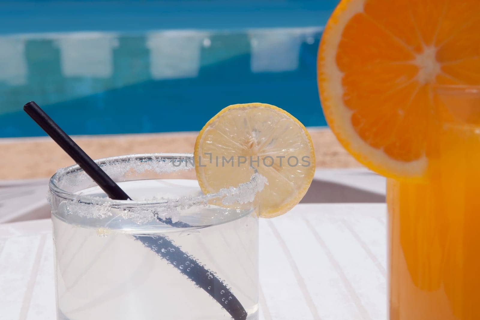 Close_up of lemonade with orange juice at the poolside