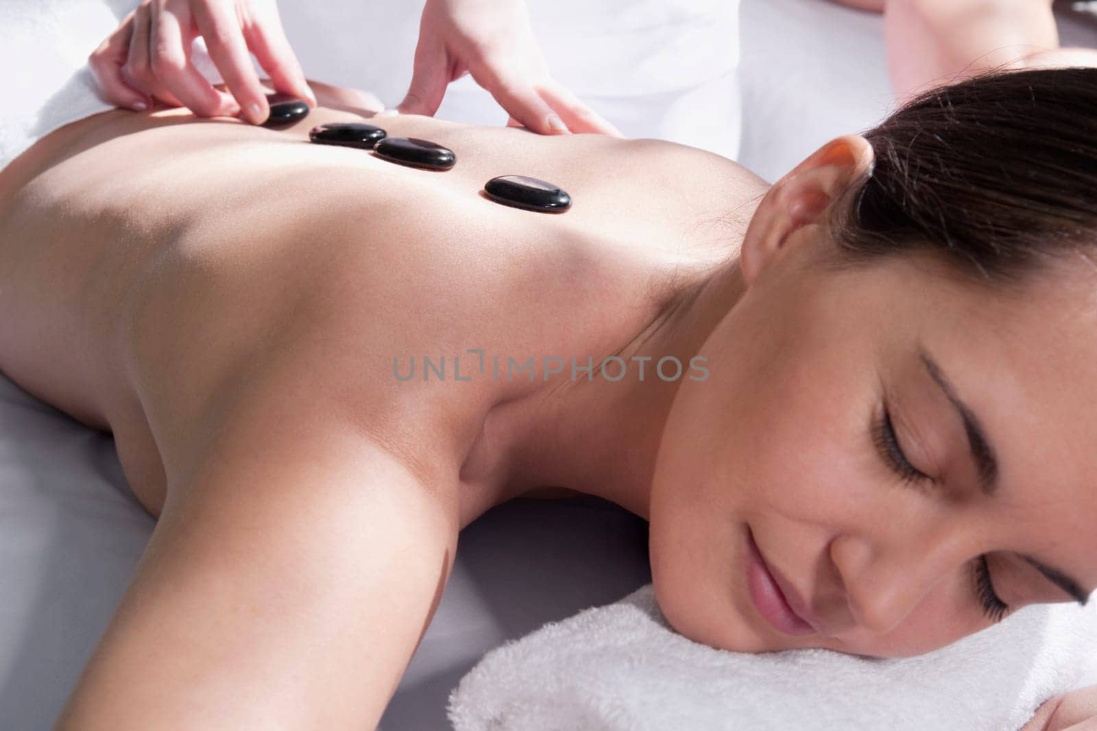 Woman receiving hot stone therapy from a massage therapist