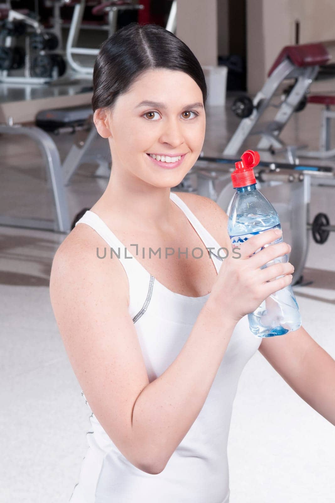 Portrait of a woman holding a water bottle in a gym