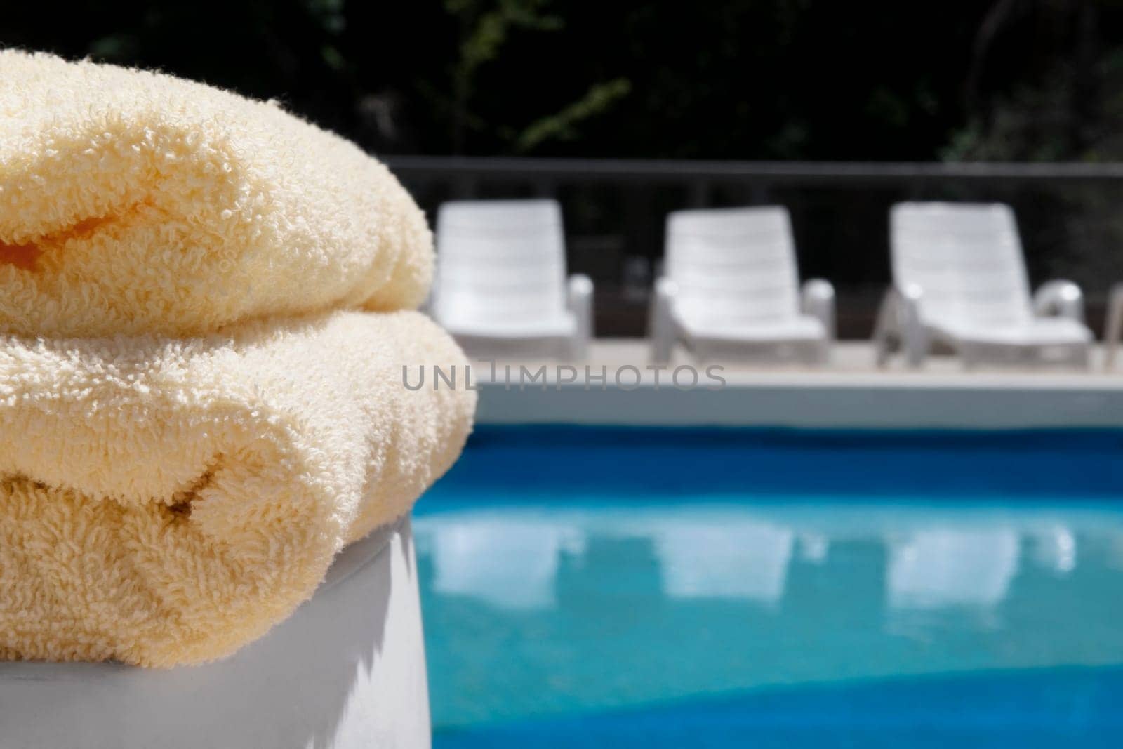 Close_up of towels and lounge chairs at the poolside