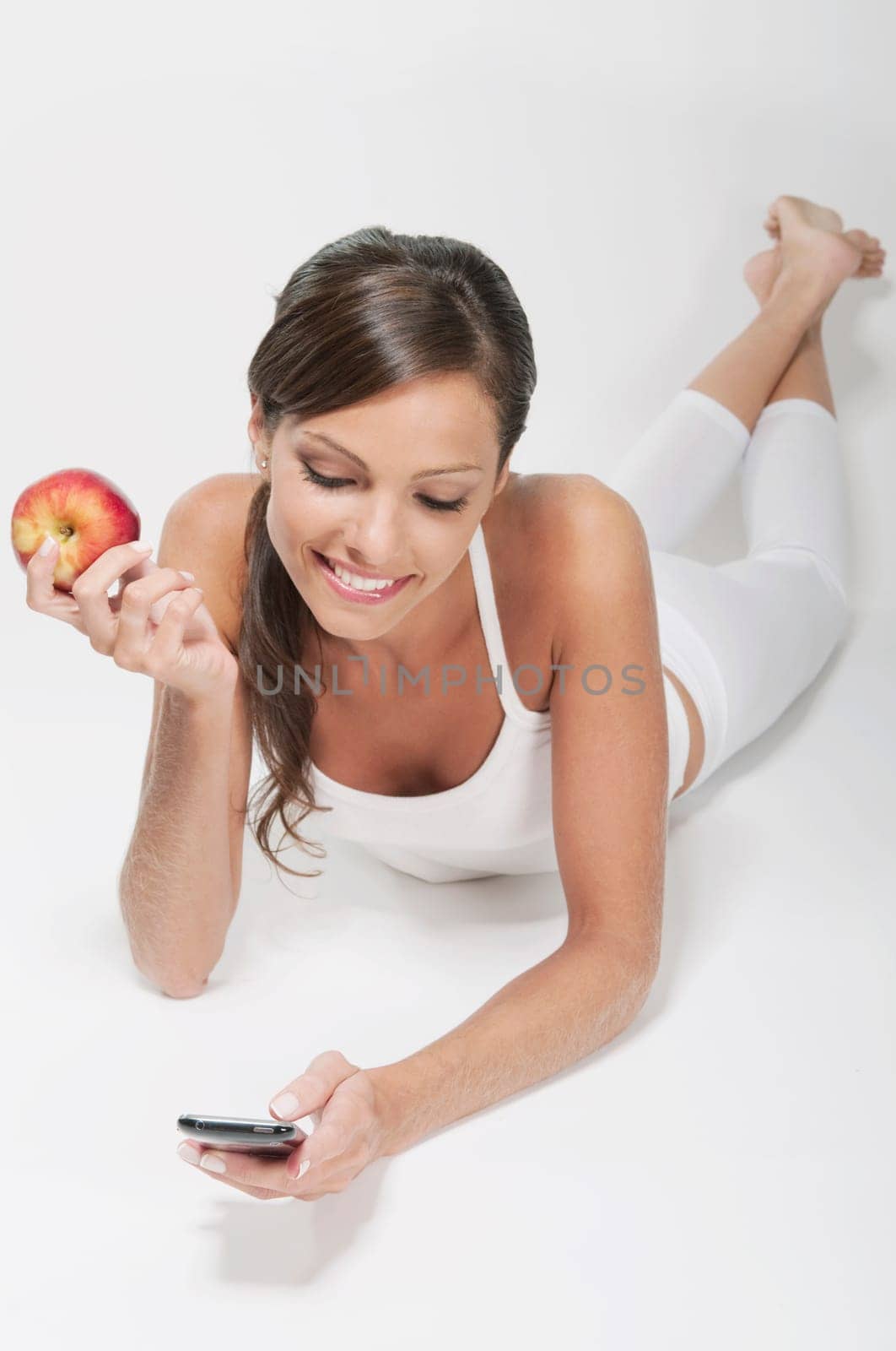 Woman holding a red apple and using a mobile phone