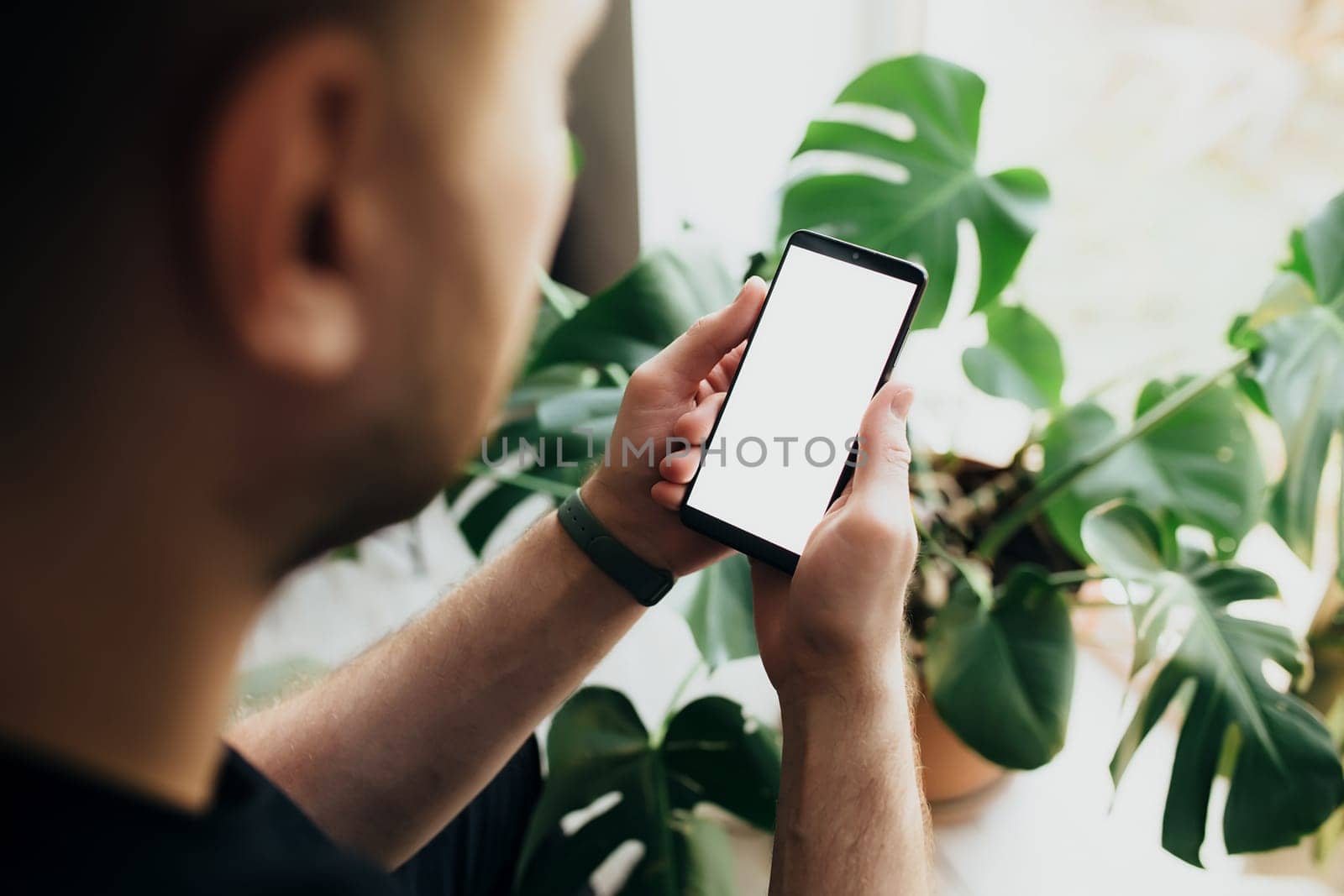 Man is holding smartphone with white screen. Blurred background. High quality photo