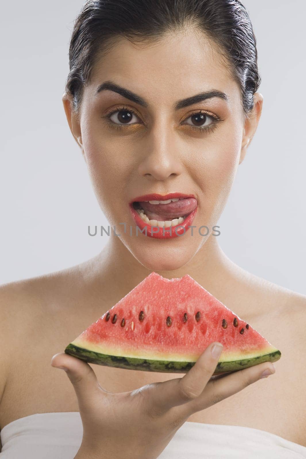 Woman holding a slice of watermelon and licking lips