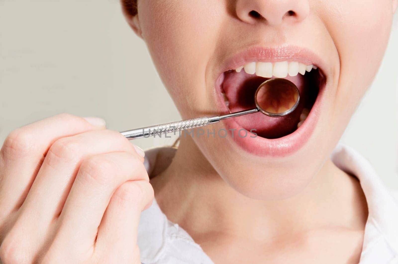 Woman examining her teeth with angled mirror