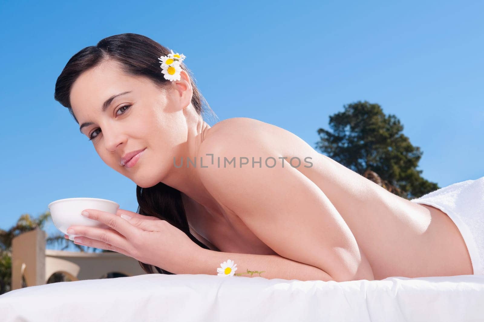 Portrait of a woman holding a bowl on a massage table