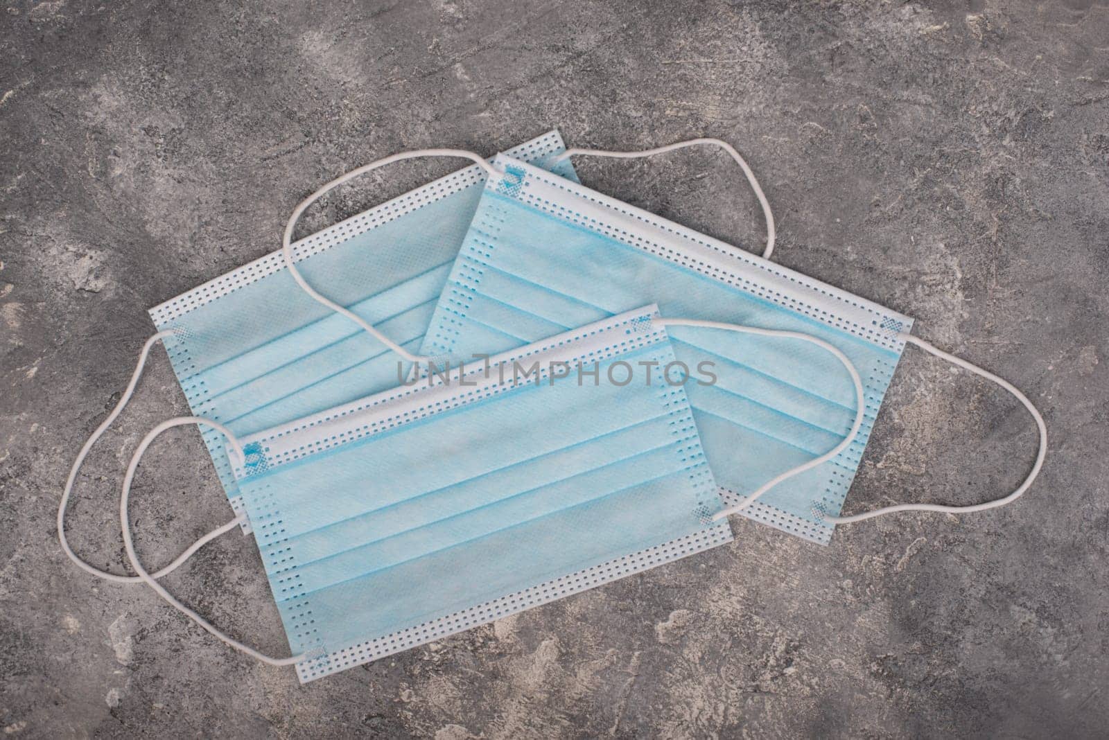 Surgeon masks to protect from Covid-19, worldwide pandemic in 2020 and 2021, blue coloured, empty copy space for text, isolated on a textured background