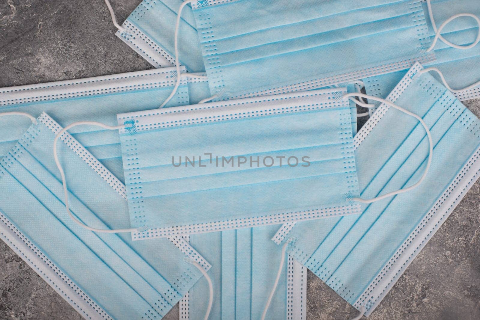 Surgeon masks to protect from Covid-19, worldwide pandemic in 2020 and 2021, blue coloured, empty copy space for text, isolated on a textured background