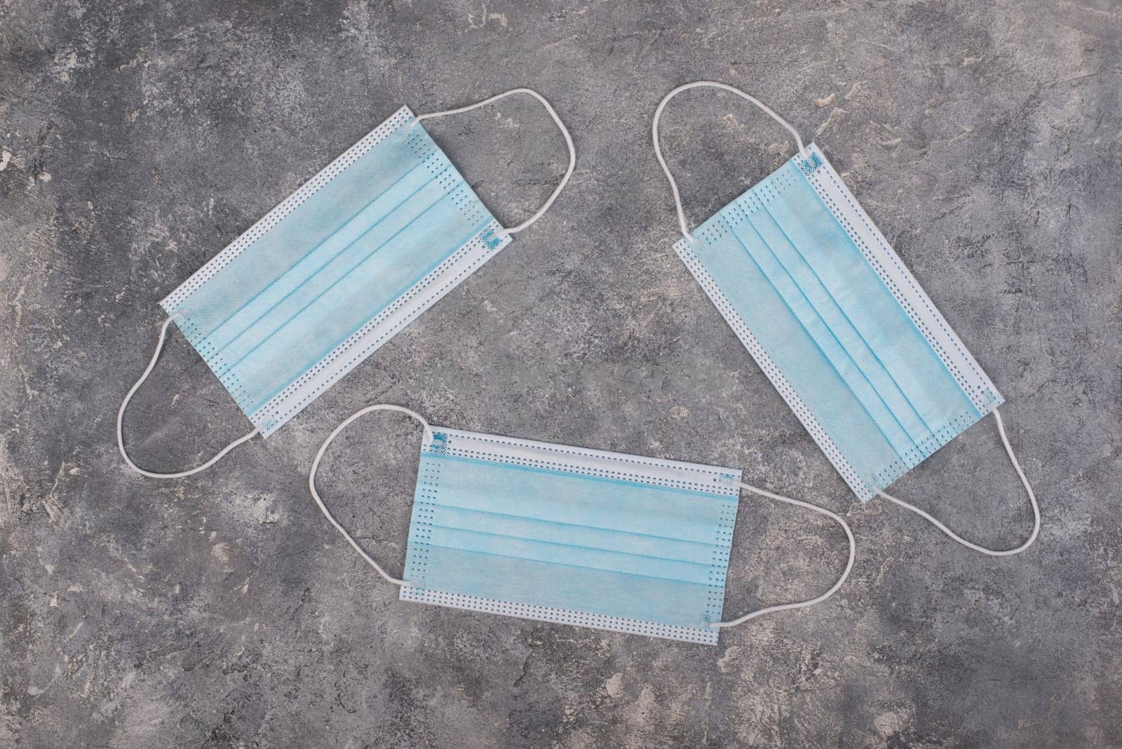 Surgeon masks to protect from Covid-19, worldwide pandemic in 2020 and 2021, blue coloured, empty copy space for text, isolated on a textured background