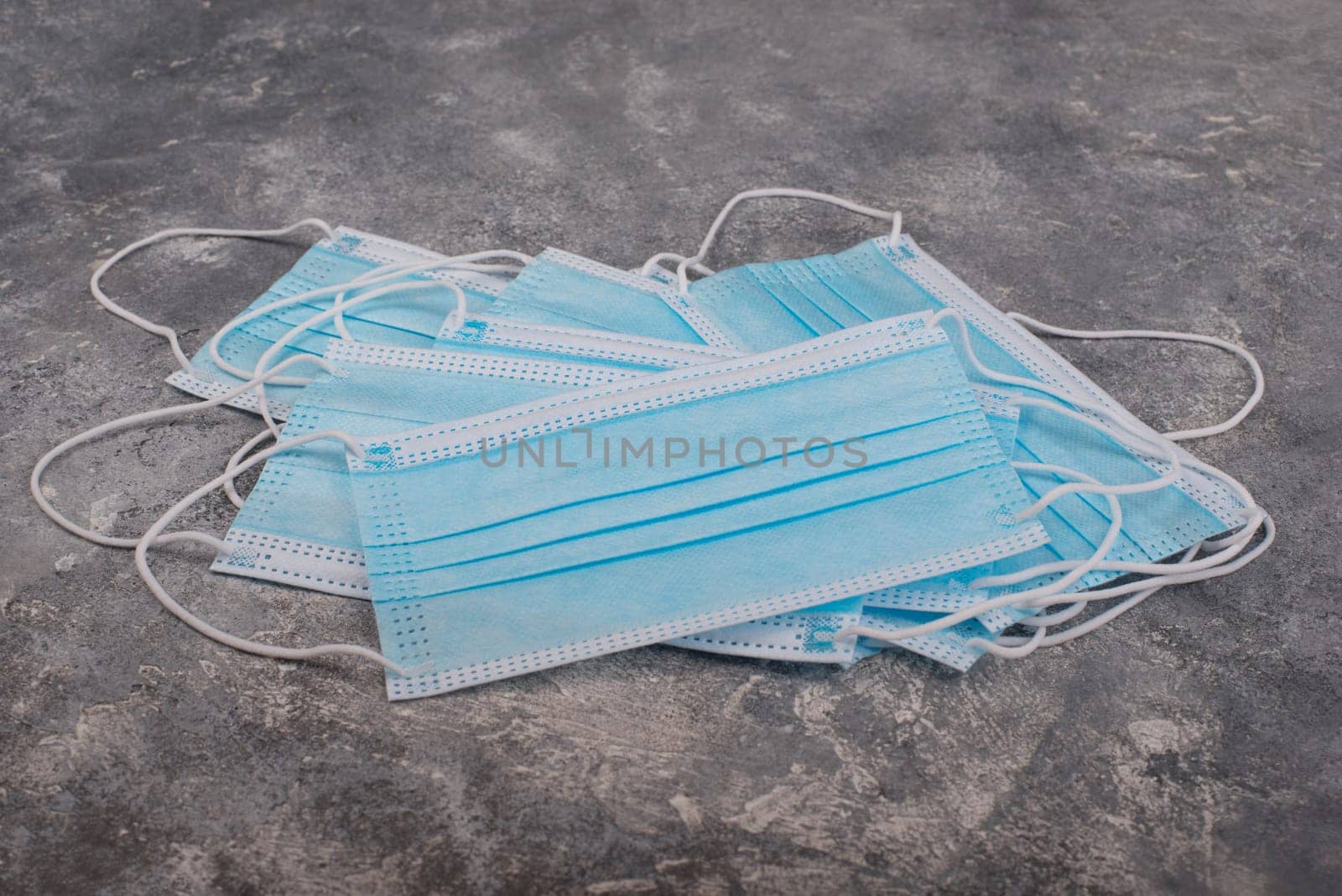 Surgeon masks to protect from Covid-19, worldwide pandemic in 2020 and 2021, blue coloured, empty copy space for text, isolated on a textured background