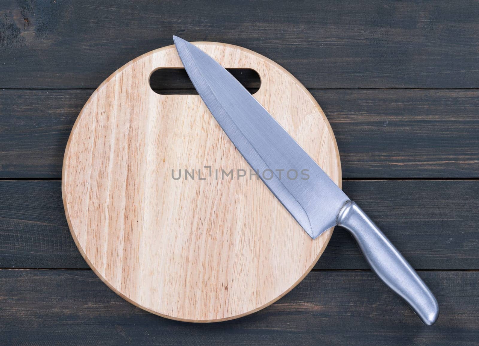 Close up kitchen knife and round cutting board on a wooden table
