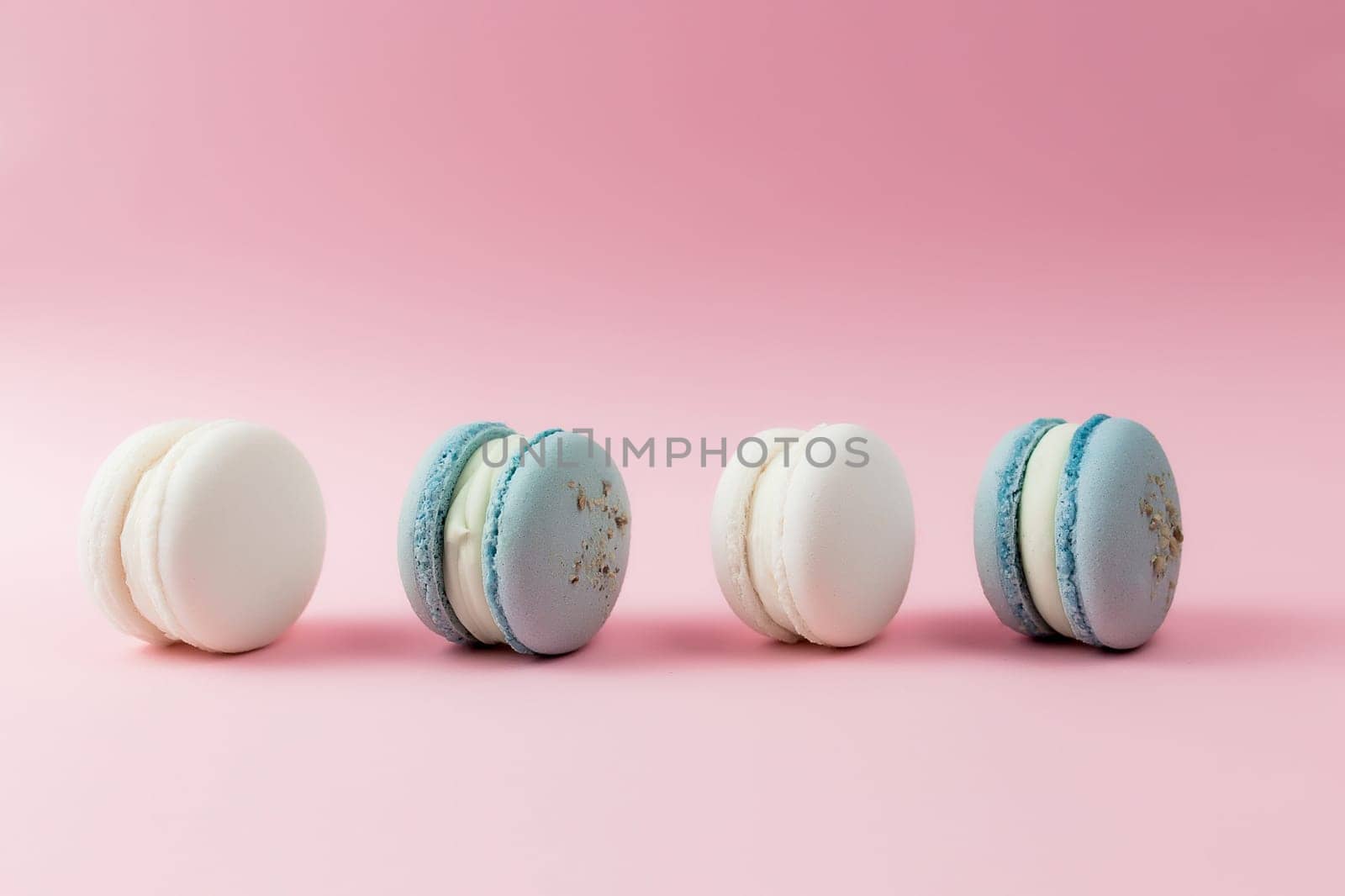 White and blue macaroons on the table, macaroons on pink background. High quality photo