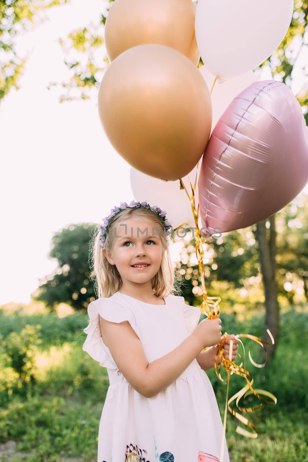 Small shiny girl with pink balloons in the garden. High quality photo