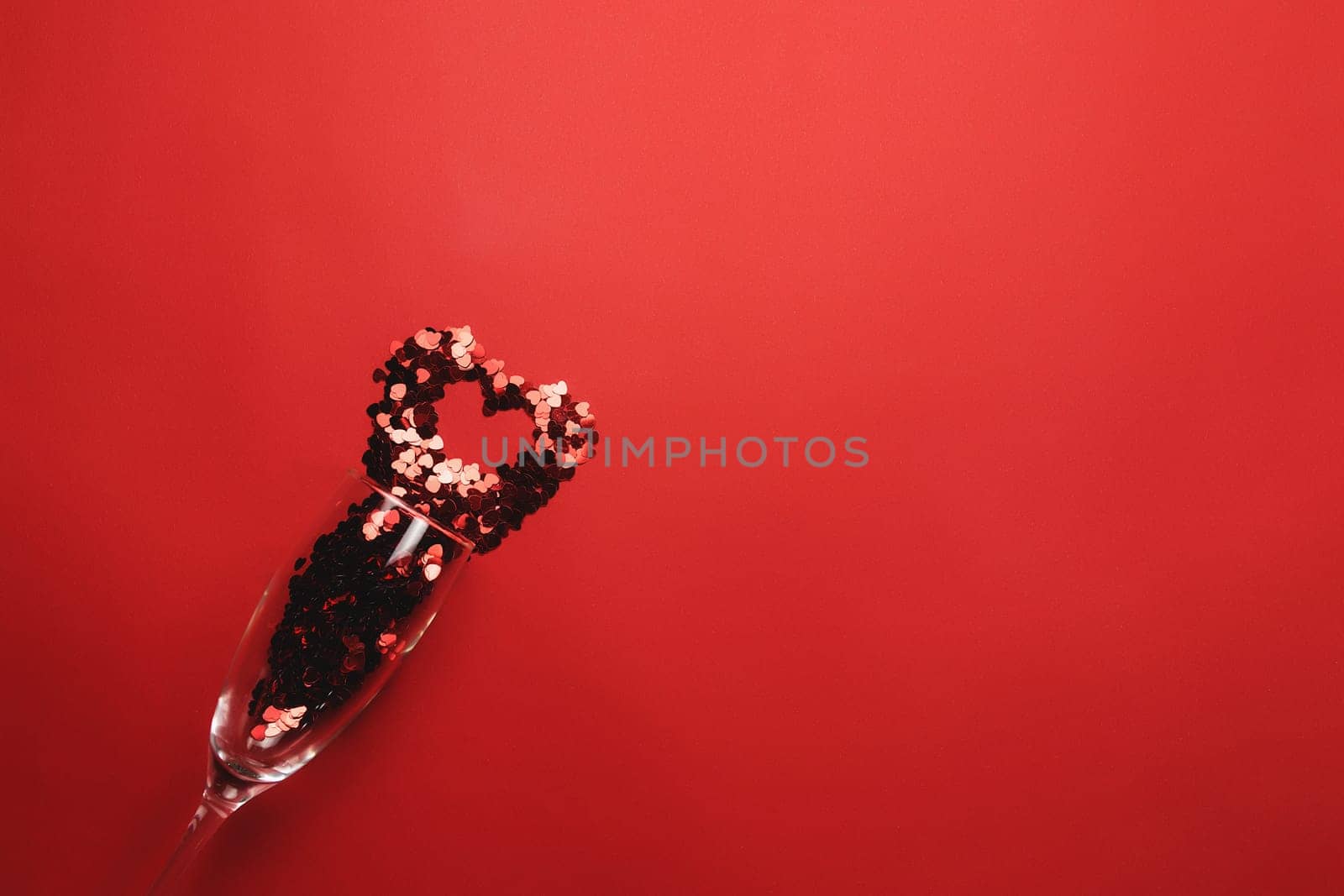 Valentine with wine glass, heart glitter on red background. High quality photo