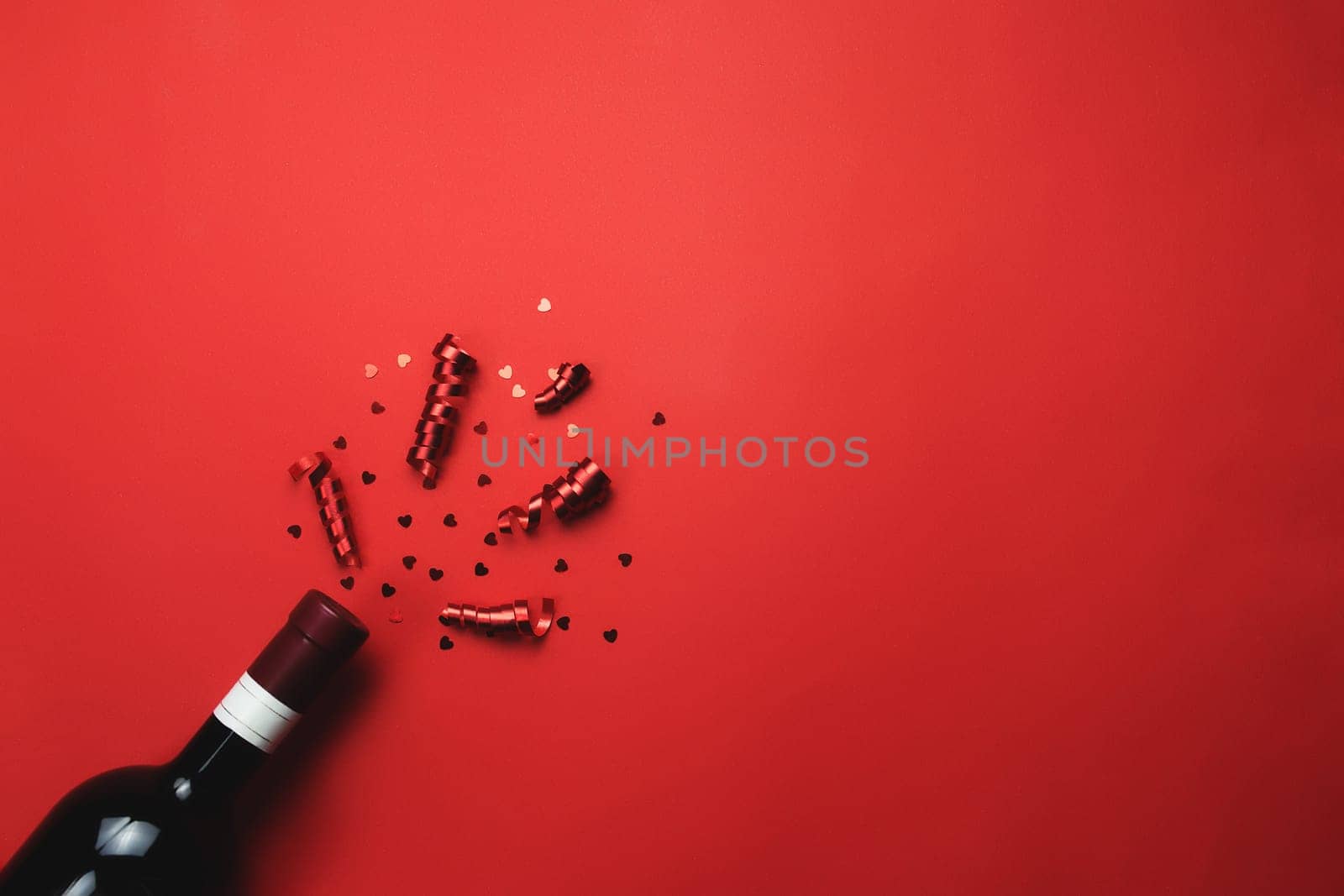 Valentine with bottle of wine, heart glitter and ribbon on red background. High quality photo